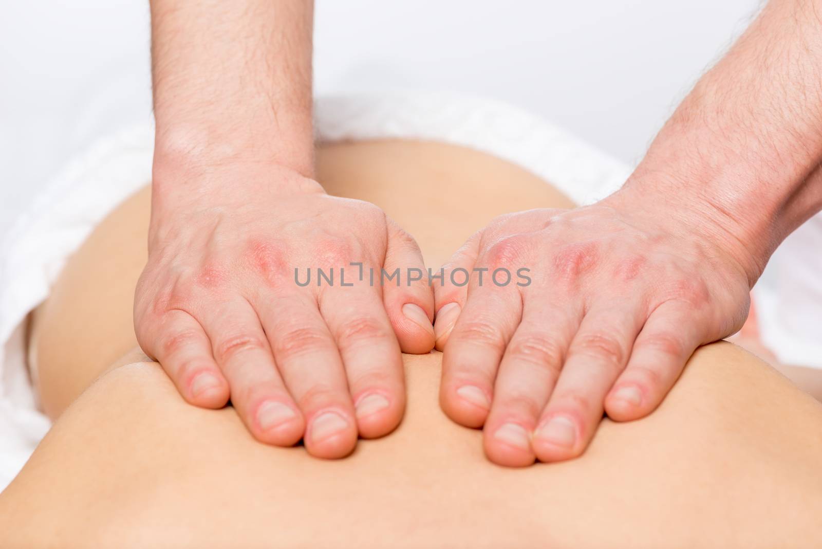 Strong masseur's hands stroking the skin of the patient