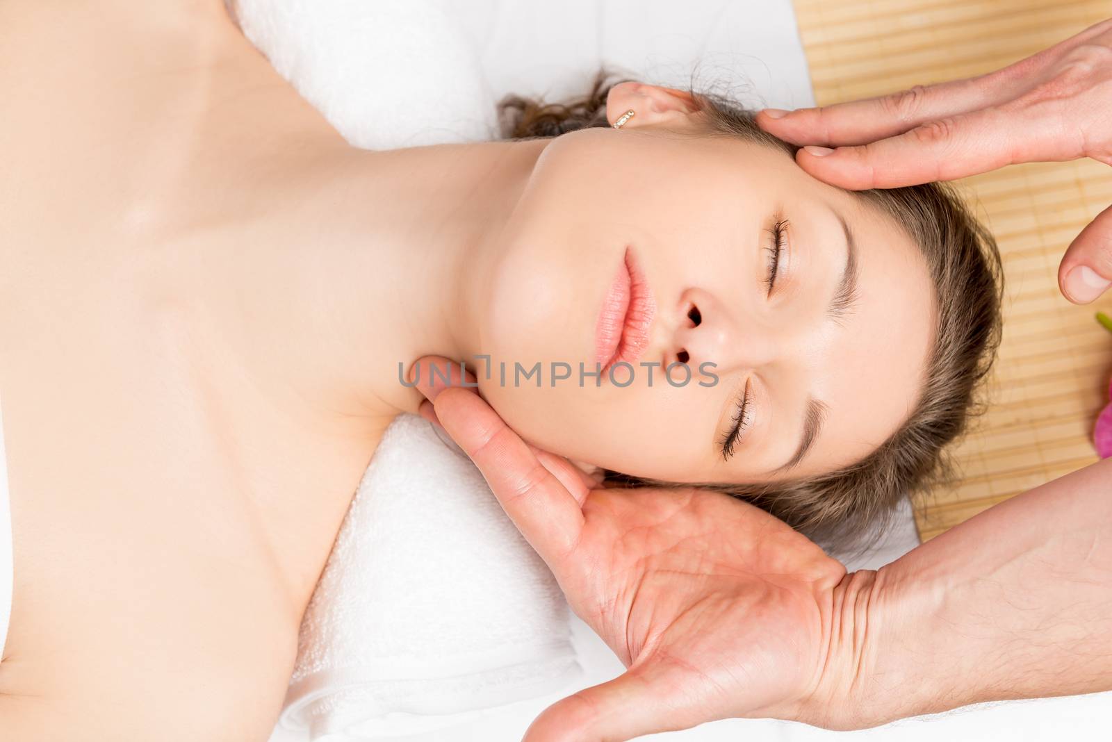 young female face with beautiful skin in the hands of a beautician, masseur