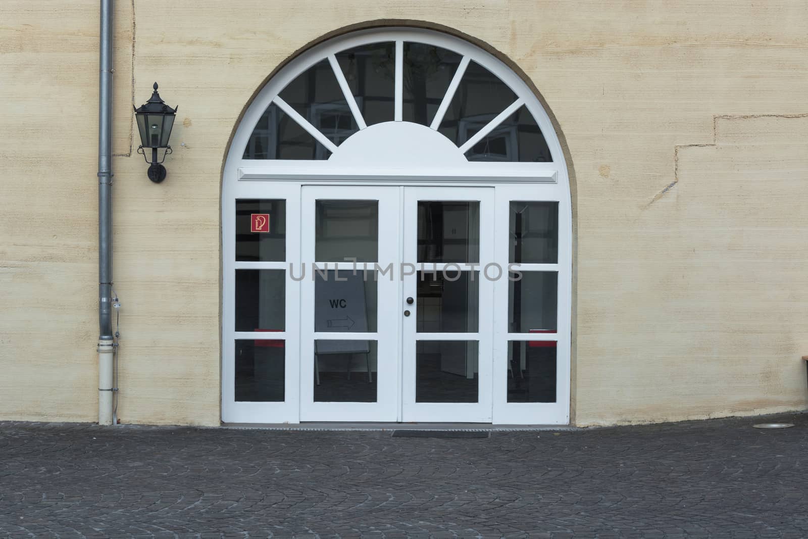New large round arch door with rungs in a yellow plastered house wall.