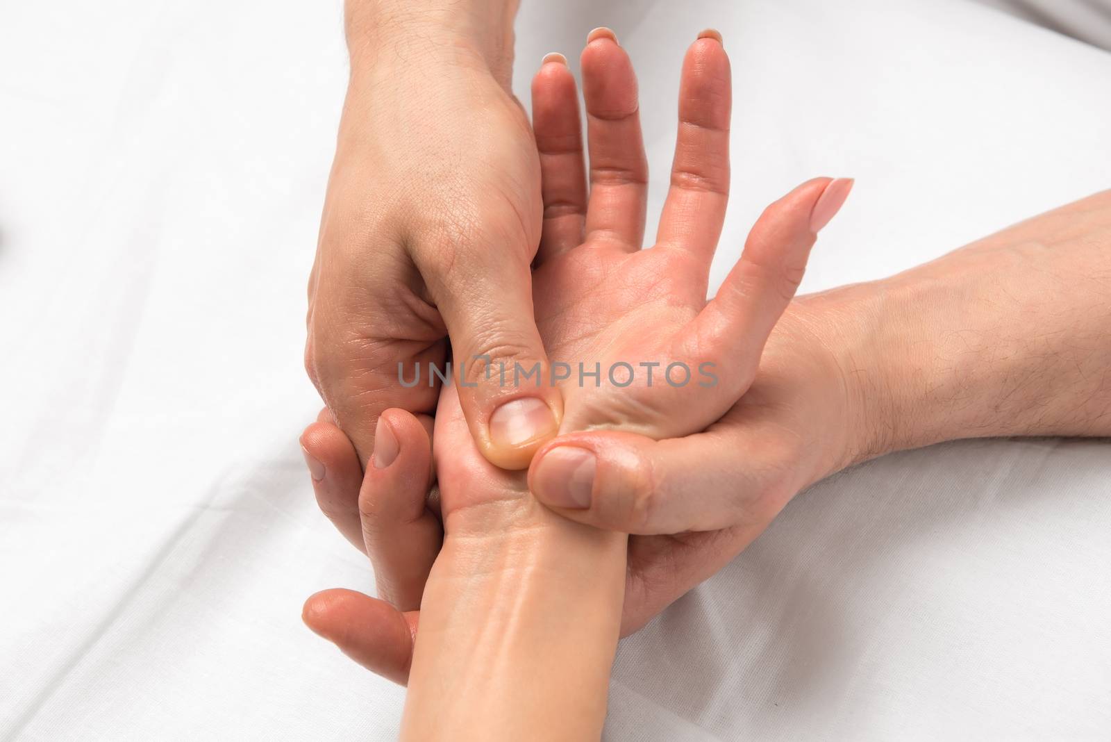 Photo of reception massage hands closeup on white sheets