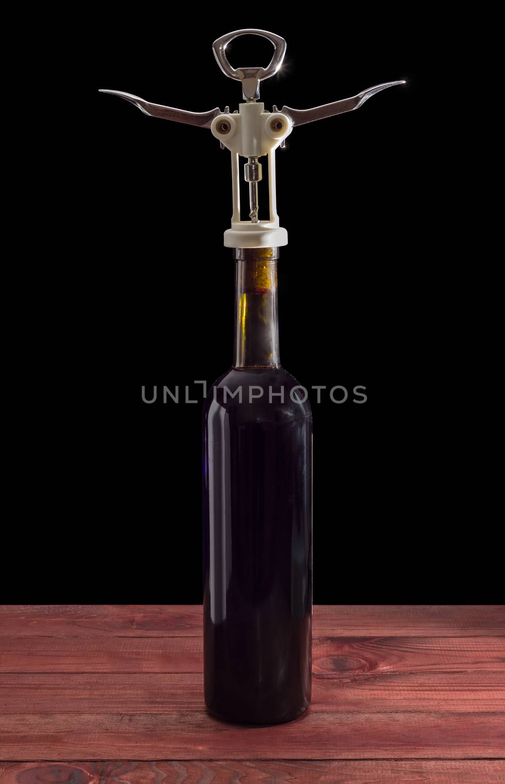 Corkscrew on a bottle of wine on a dark background  by anmbph