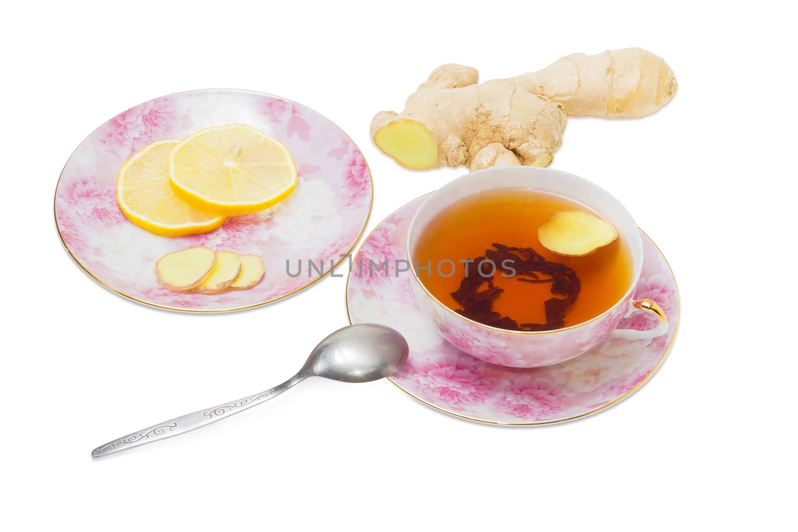 Cup of ginger tea on pink saucer, a tea spoon and saucer with slices of a ginger and lemon against the backdrop of ginger root on a light background
