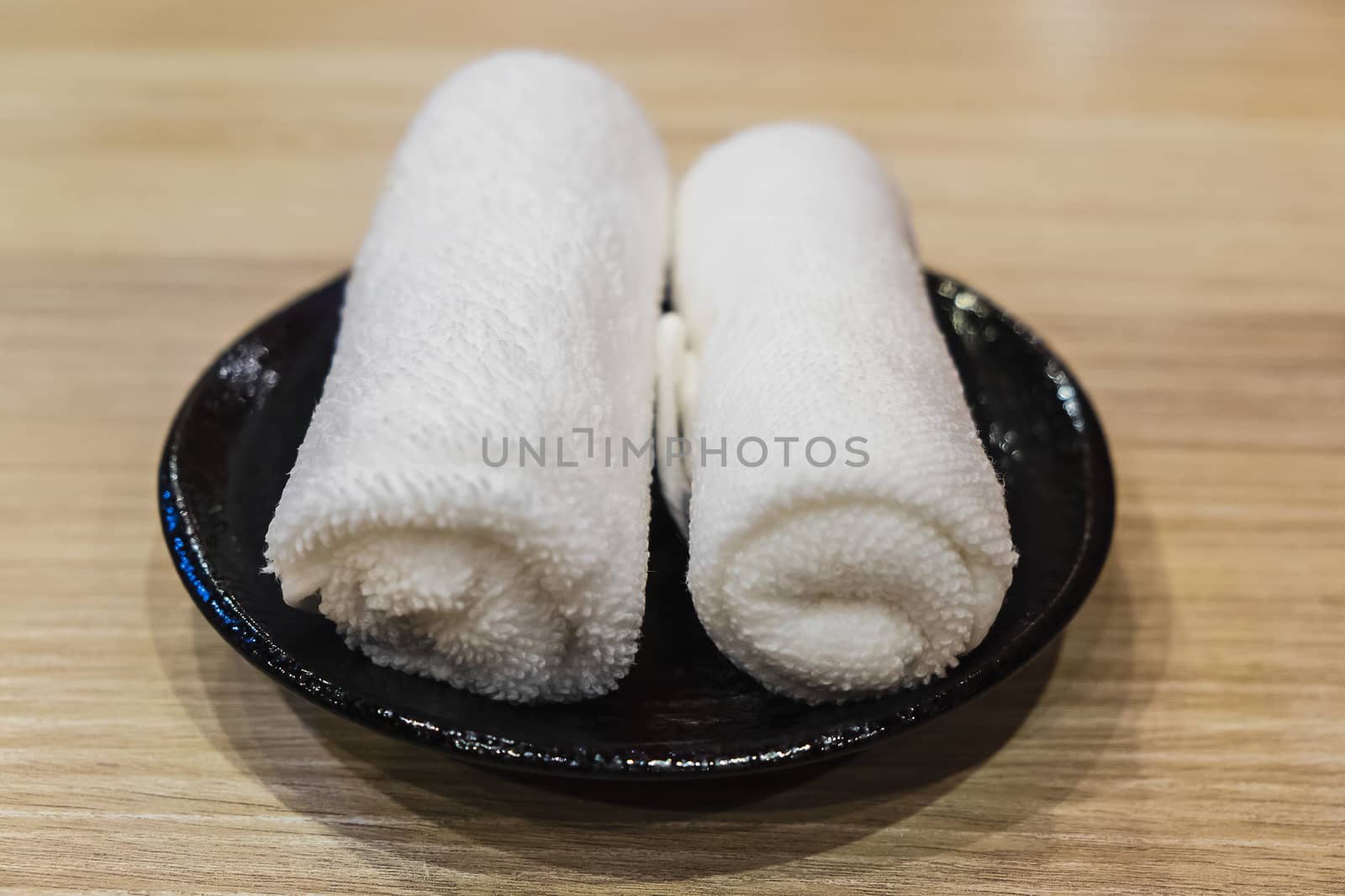 rolled set of hot wet towel (oshibori) on black dish by luckyfim