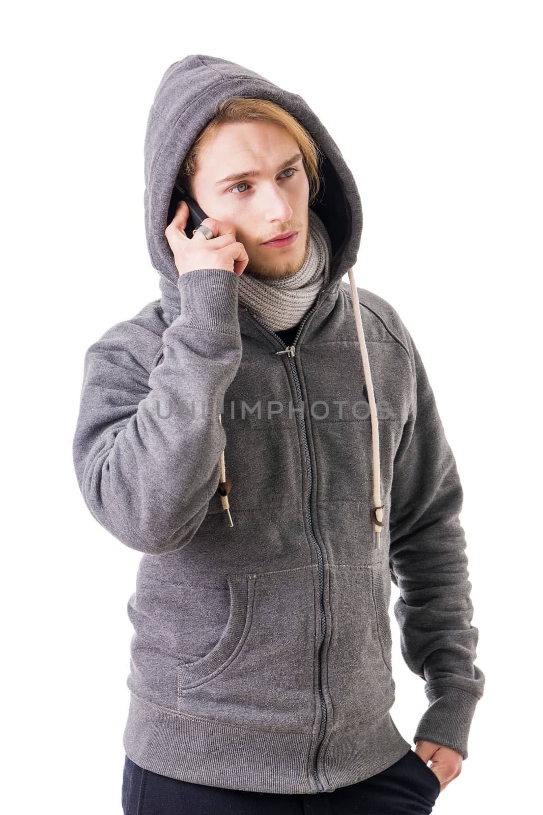 Attractive young man in winter clothes talking on cellphone, having a conversation, isolated on white