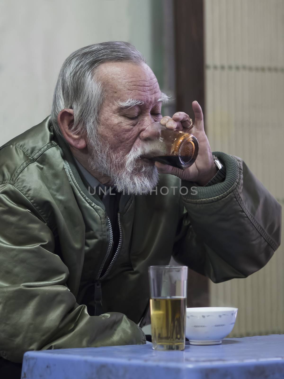Hue, Vietnam - Dec 30, 2016: Old man savoring the intense pleasure of strong and dark vietnamese coffee at a cafe.