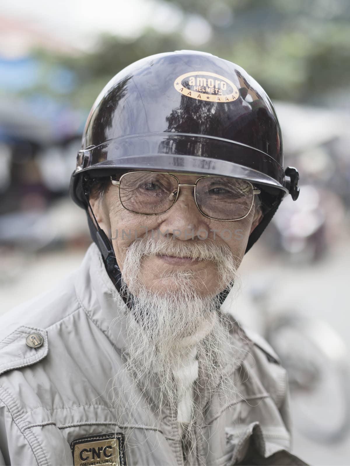 Hoi An, Vietnam - Dec 28, 2016: Portrait of an old biker in Hoi An who keeps his goatee like his hero Ho Chi Minh.