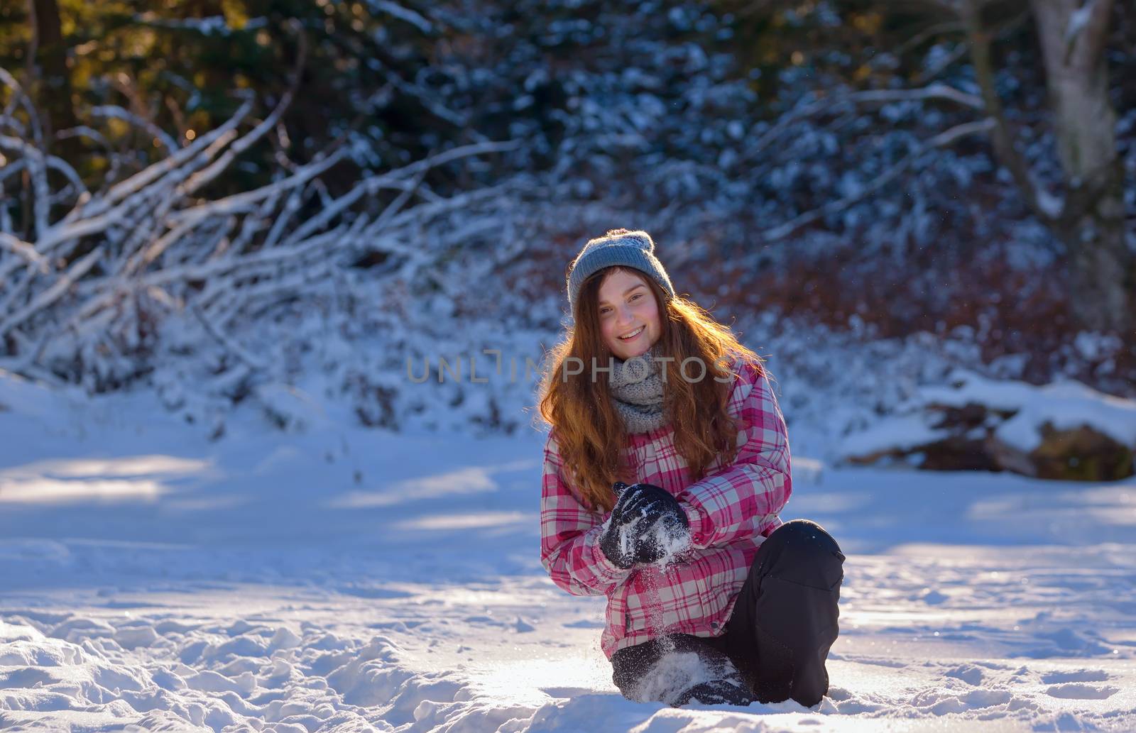 teen girl playing in snow throwing snowball at camera