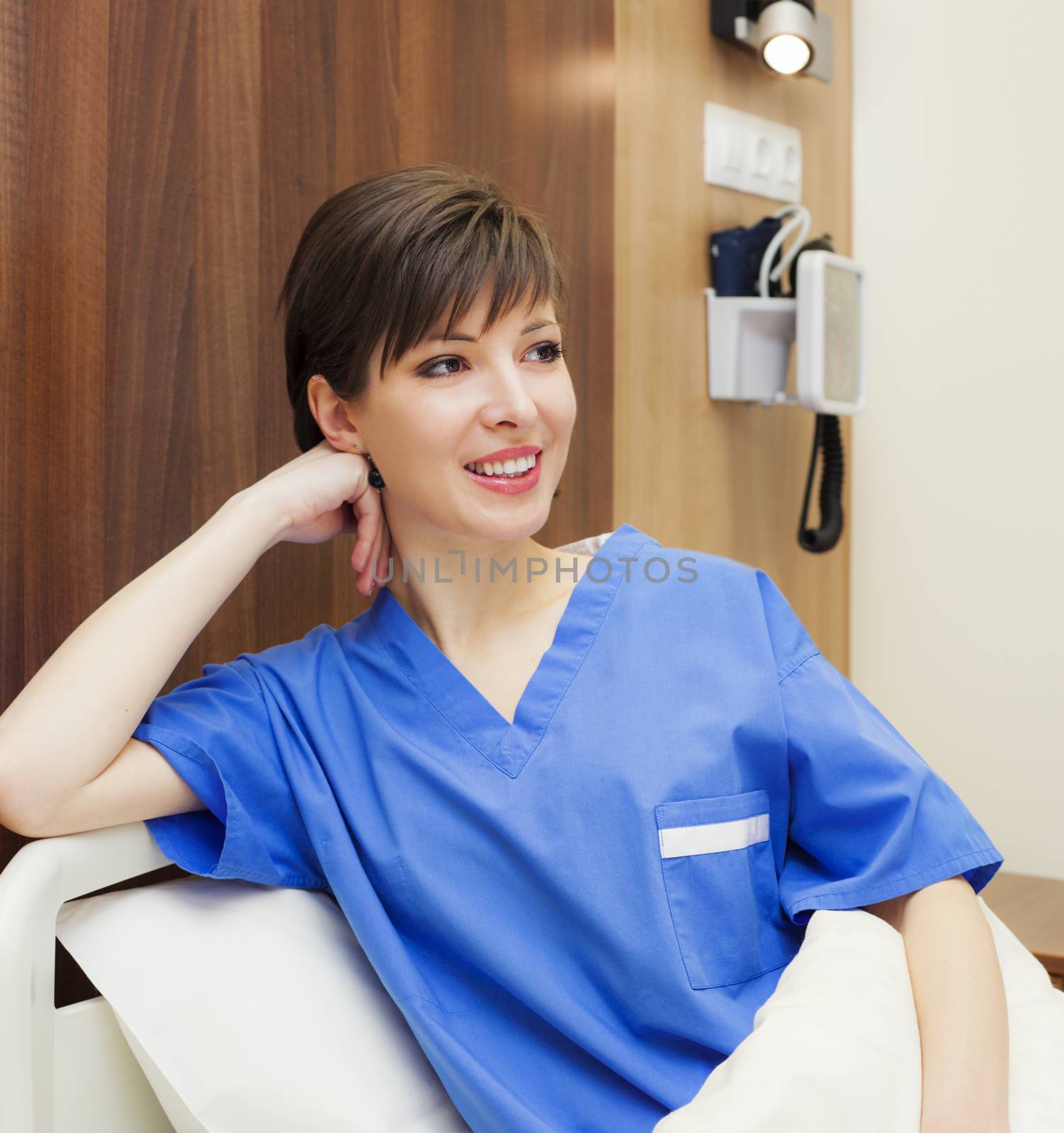 A happy smiling recovering young female patient lying in modern hospital bed.