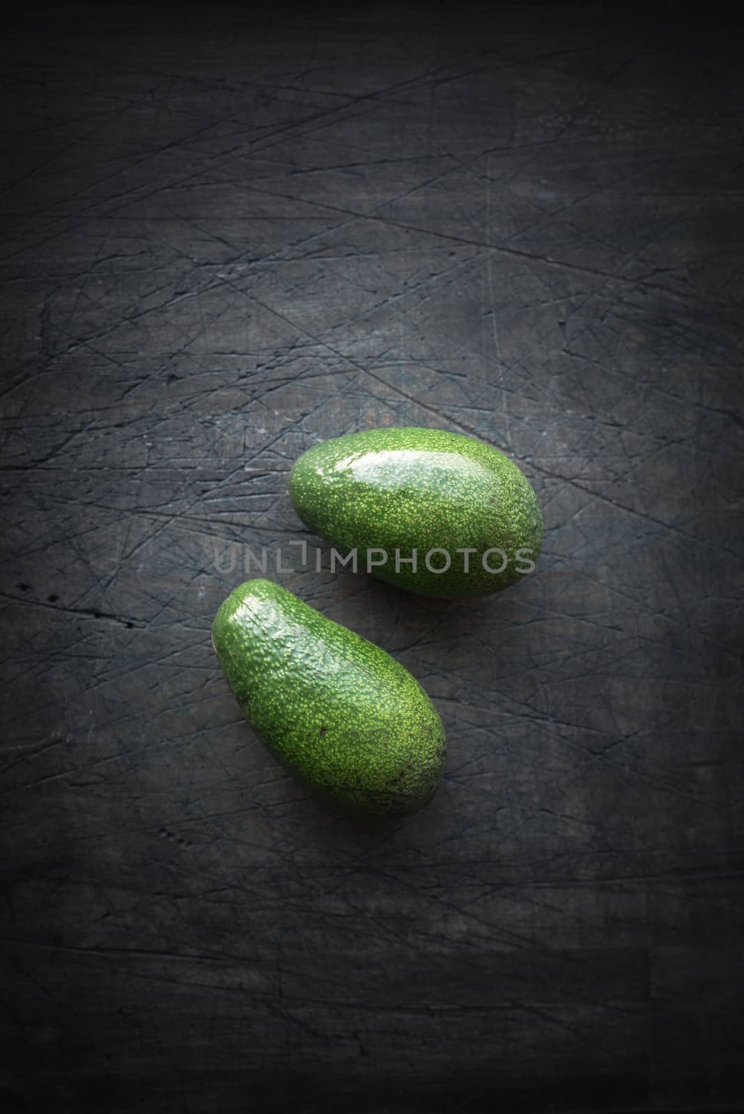 Avocado on the dark scratched table top view by Deniskarpenkov