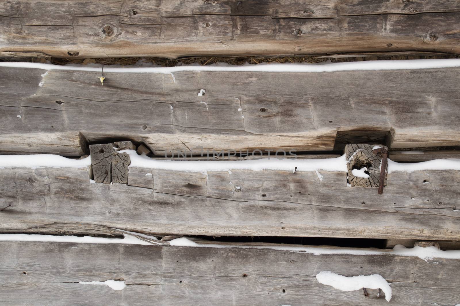 A festive winter background with weathered silvery grey horizontal sawn logs with snow in between.