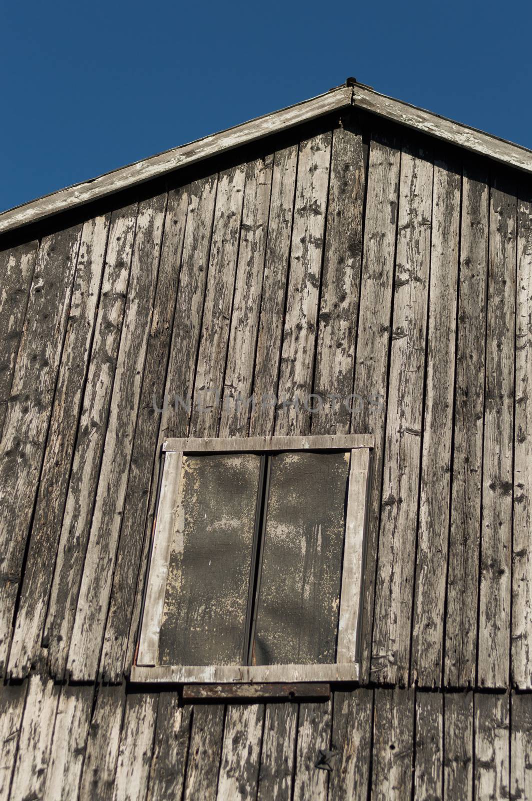 Closeup of old rustic black peeling barn with deep blue sky by Sublimage