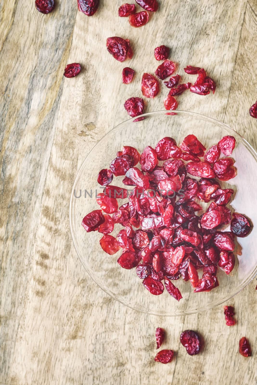 Dried cranberries in the glass bowl on the wooden table by Deniskarpenkov