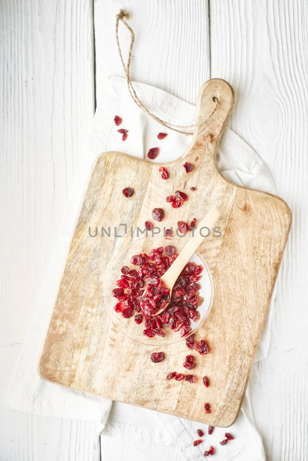 Dried cranberries in the glass bowl on the  white wooden table top view