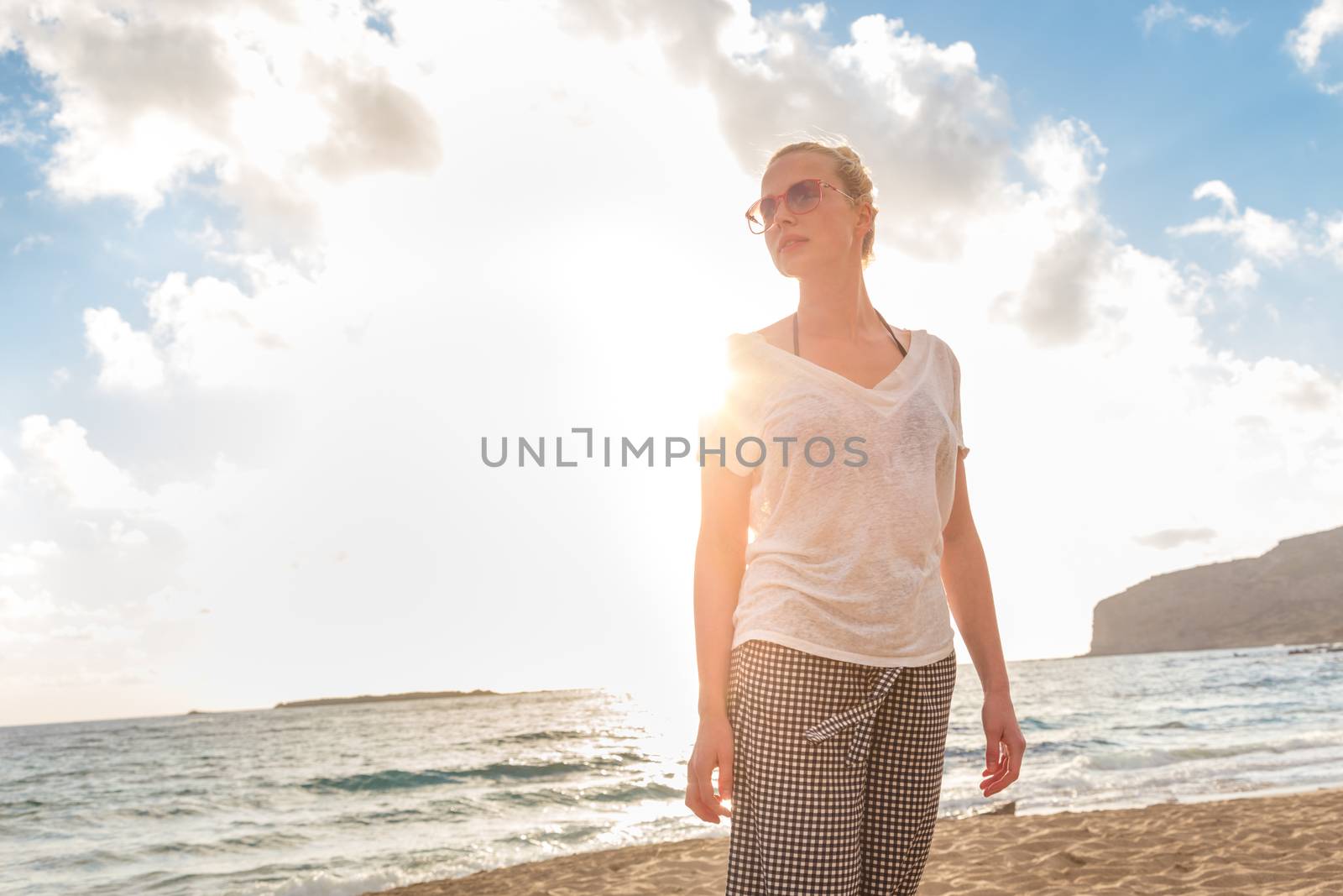 Relaxed woman enjoying sun, freedom and life an a beautiful sandy beach. Young lady feeling free, relaxed and happy. Vacations, freedom, happiness, enjoyment and well being.