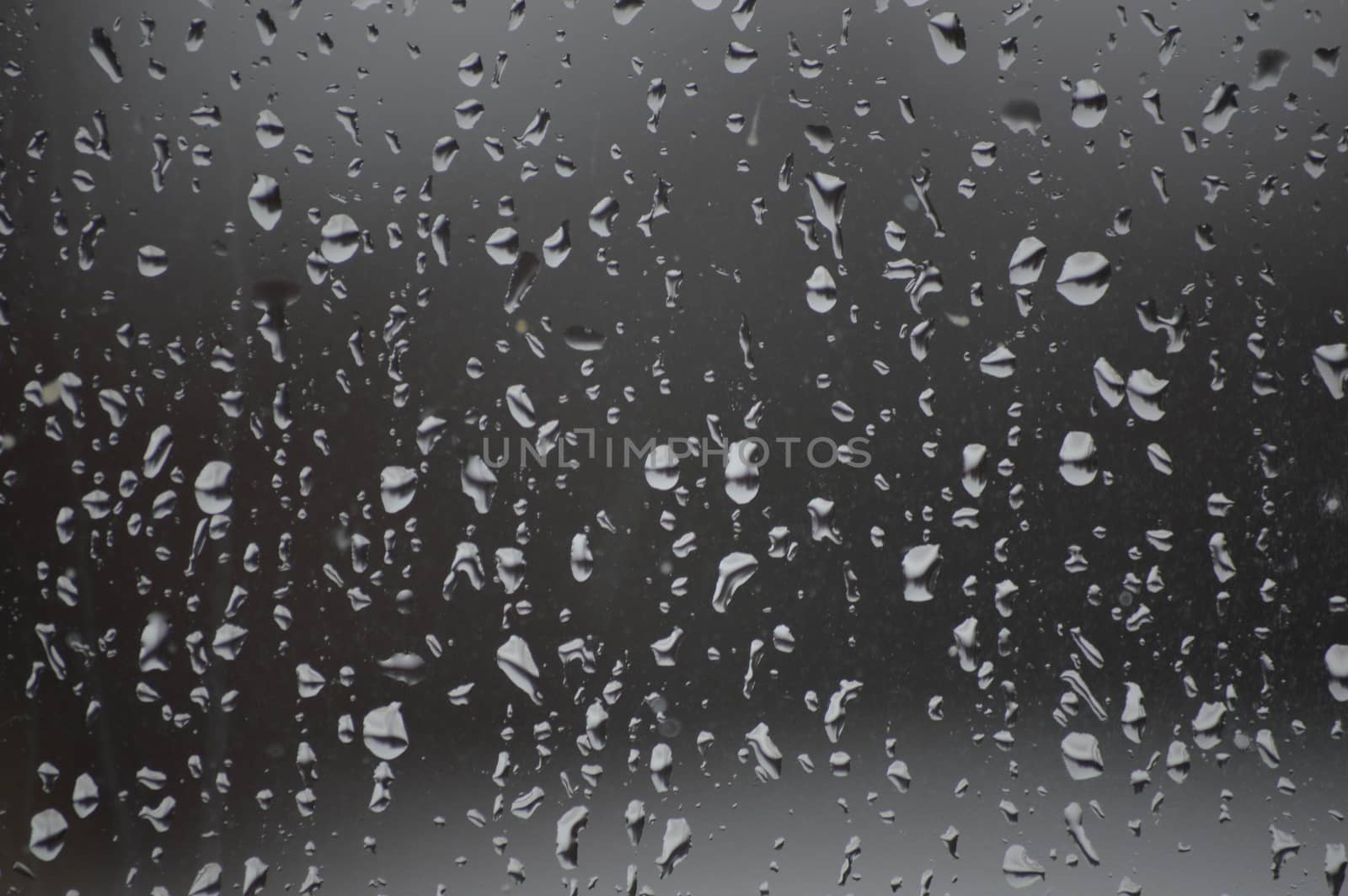 The image shows the pane only and  background is darker and the raindrops lighter.   The rain drops are even over the glass