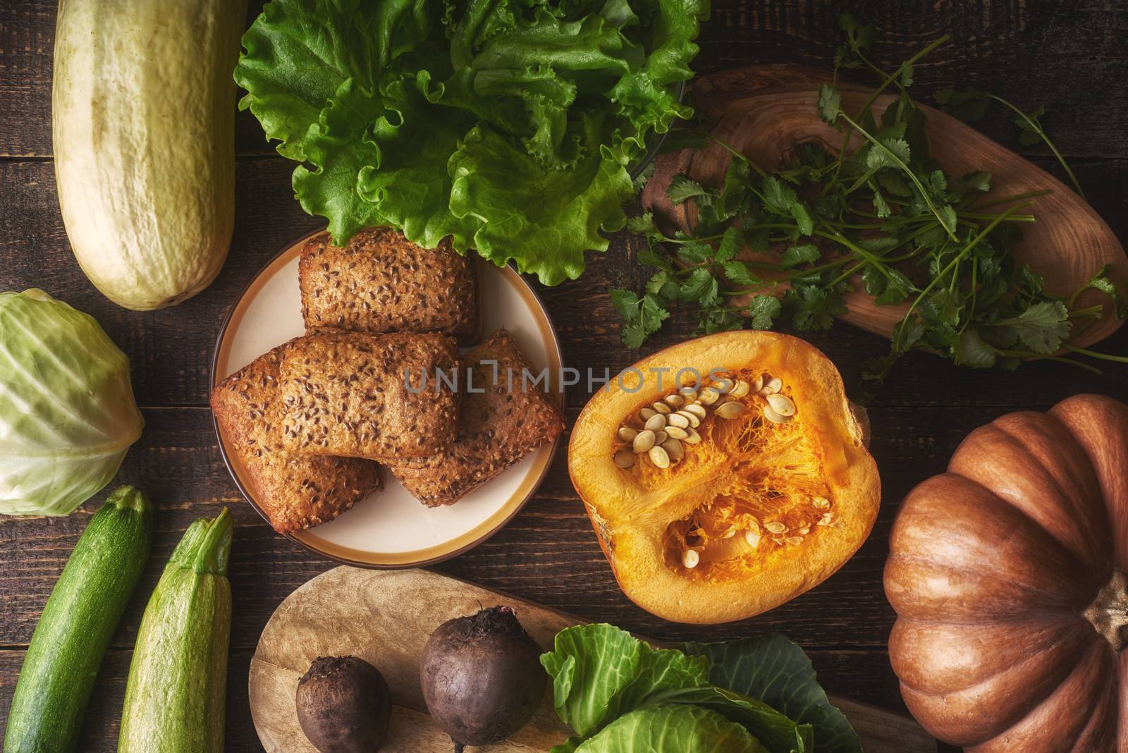 Grain bread with different vegetable on the wooden table top view