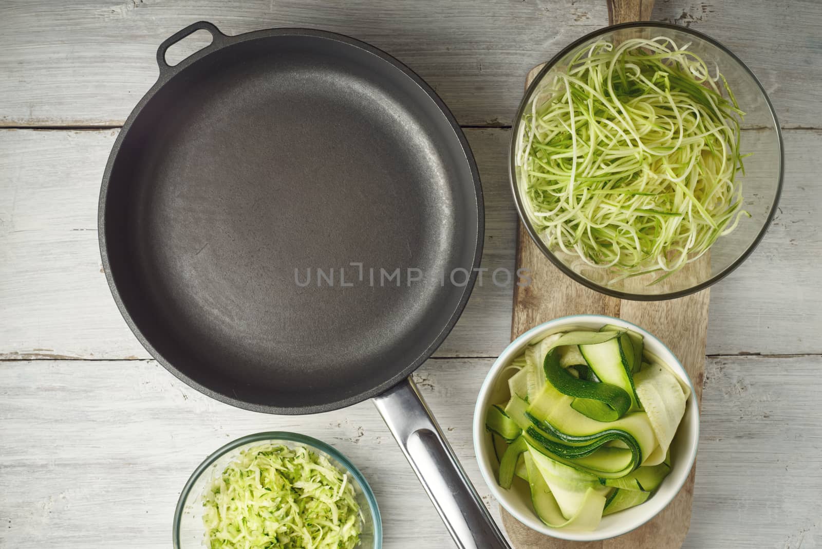 Raw zucchini noodles  with pan on the white wooden table by Deniskarpenkov