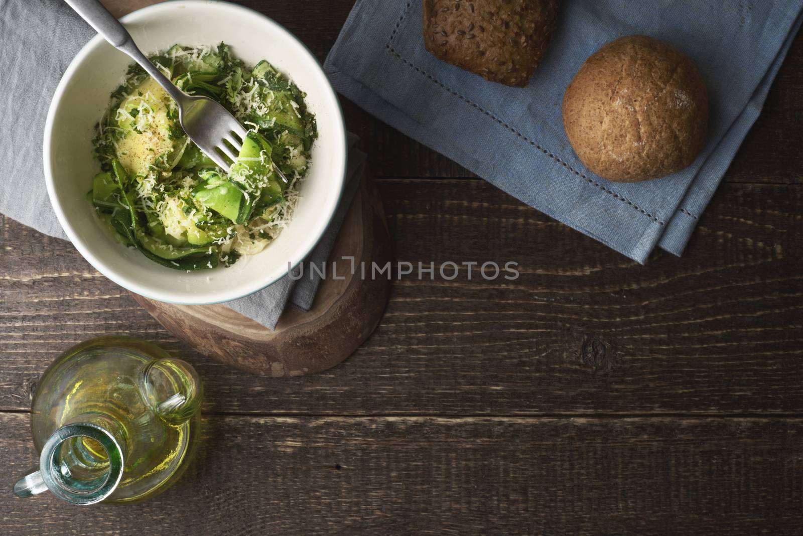Zucchini noodles with cheese and olive oil on the wooden table top view by Deniskarpenkov