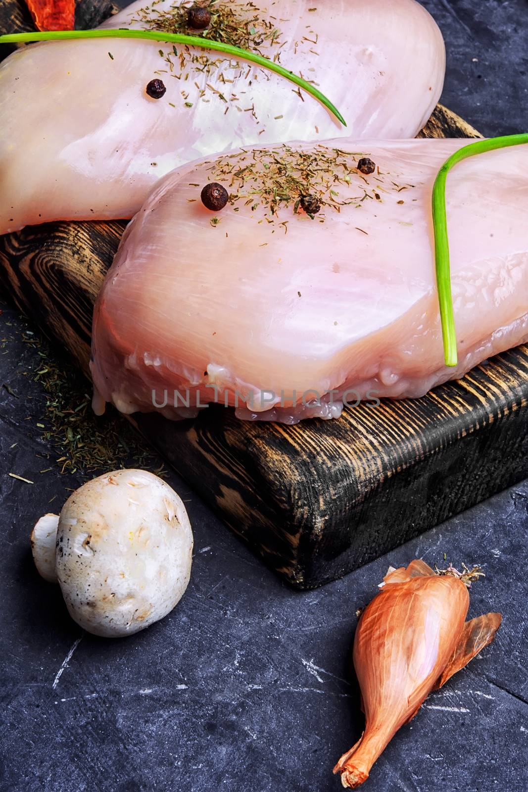 chicken raw fillets on kitchen plate with spices and mushrooms