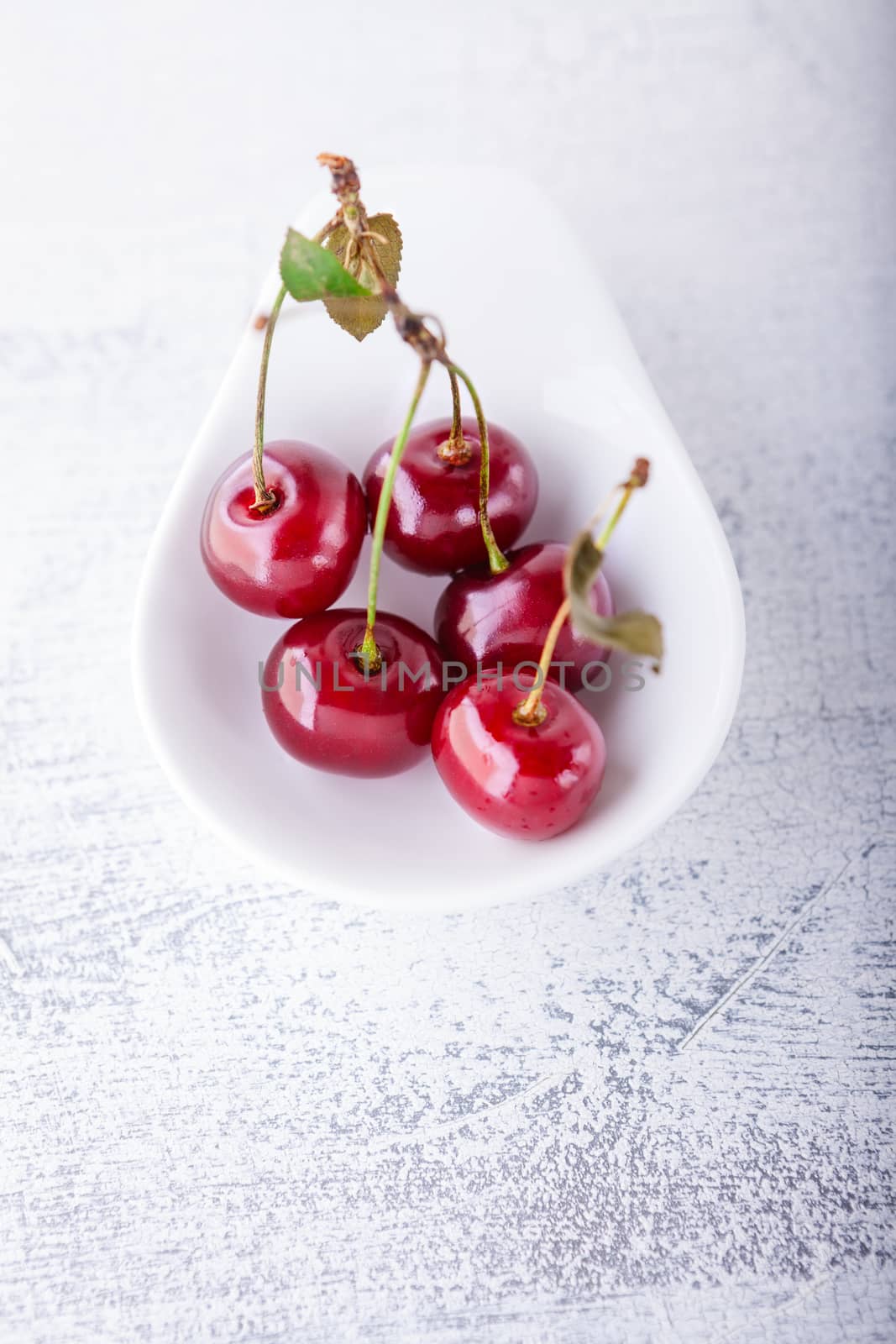 Cherries in a white dish on a wooden table 