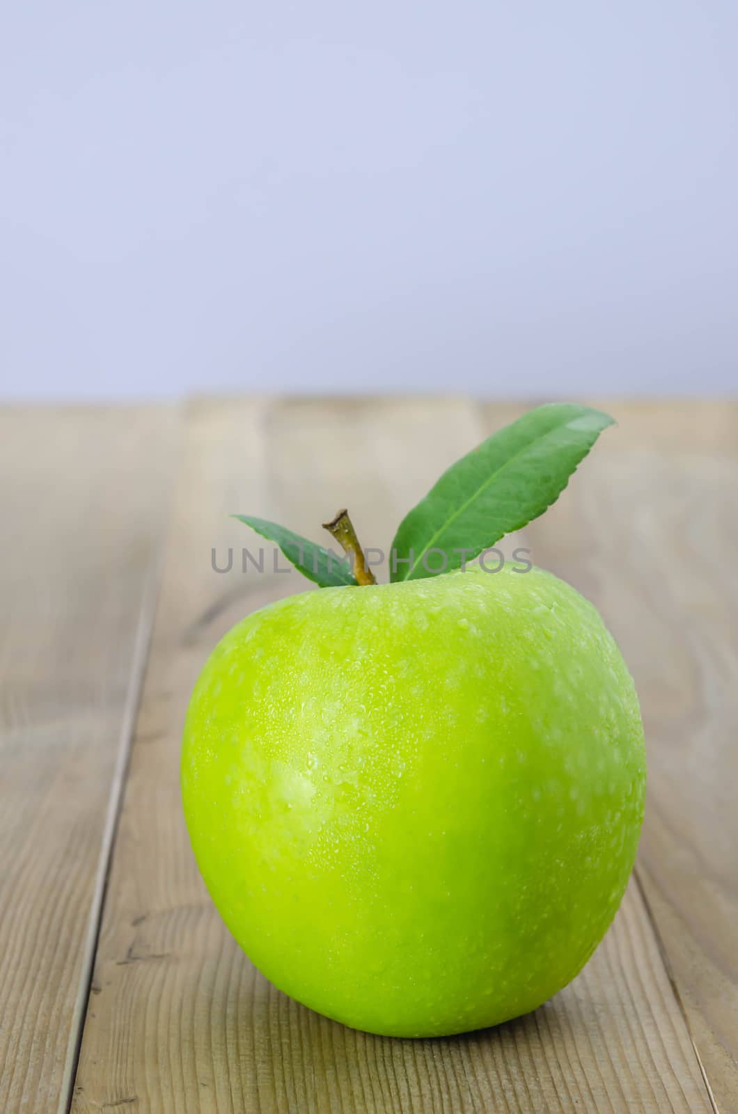 Ripe green apple with leaf  on a wooden background