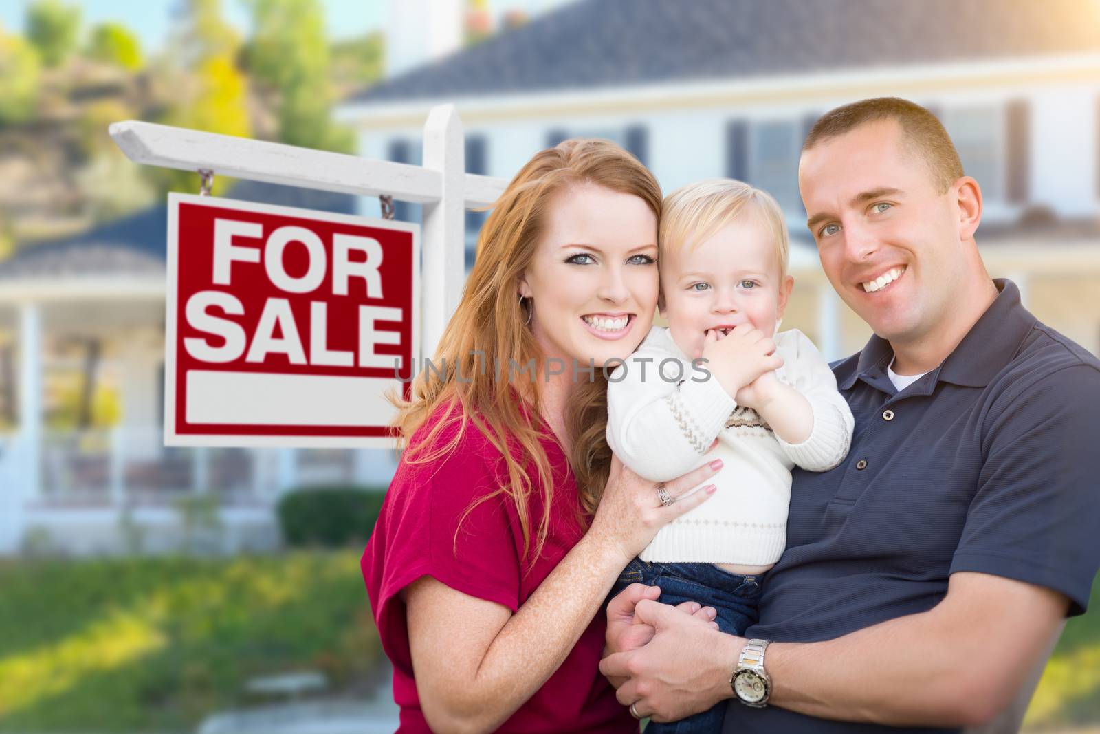 Young Military Family in Front of For Sale Sign and House by Feverpitched