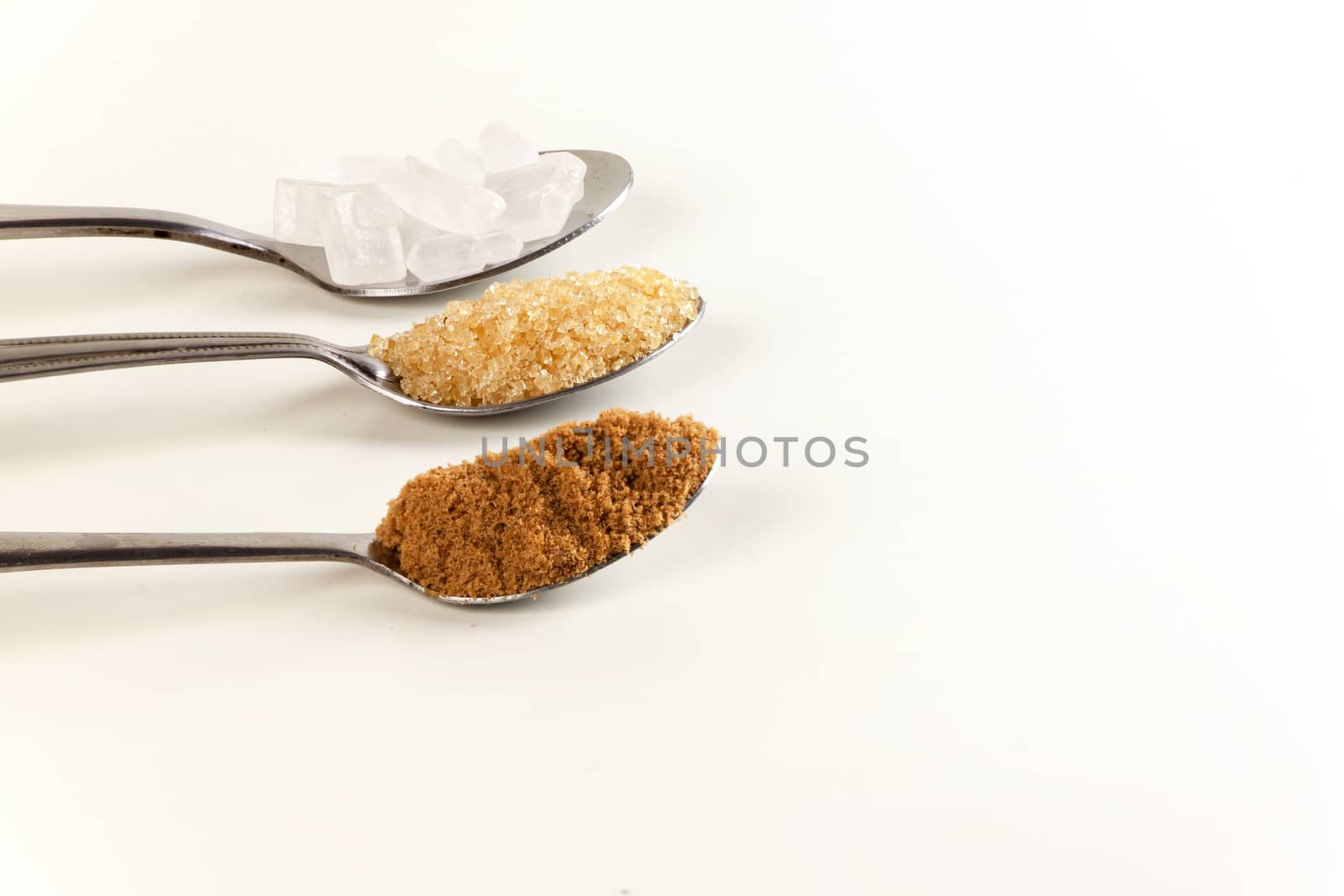 Brown cane sugar in a metal spoon on the white background. Pure cane sugar for natural. no additives.