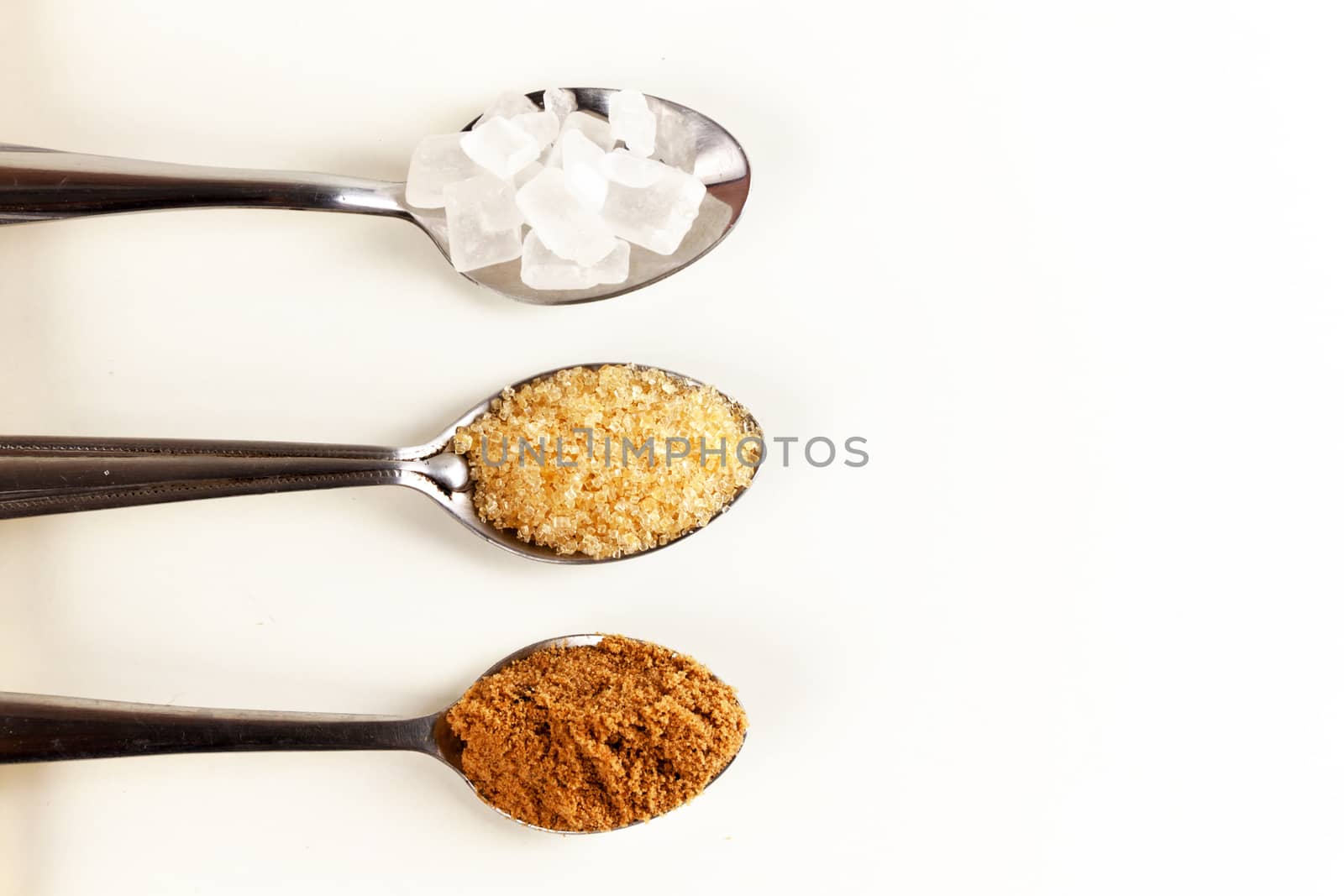 Brown cane sugar in a metal spoon on the white background. Pure cane sugar for natural. no additives.