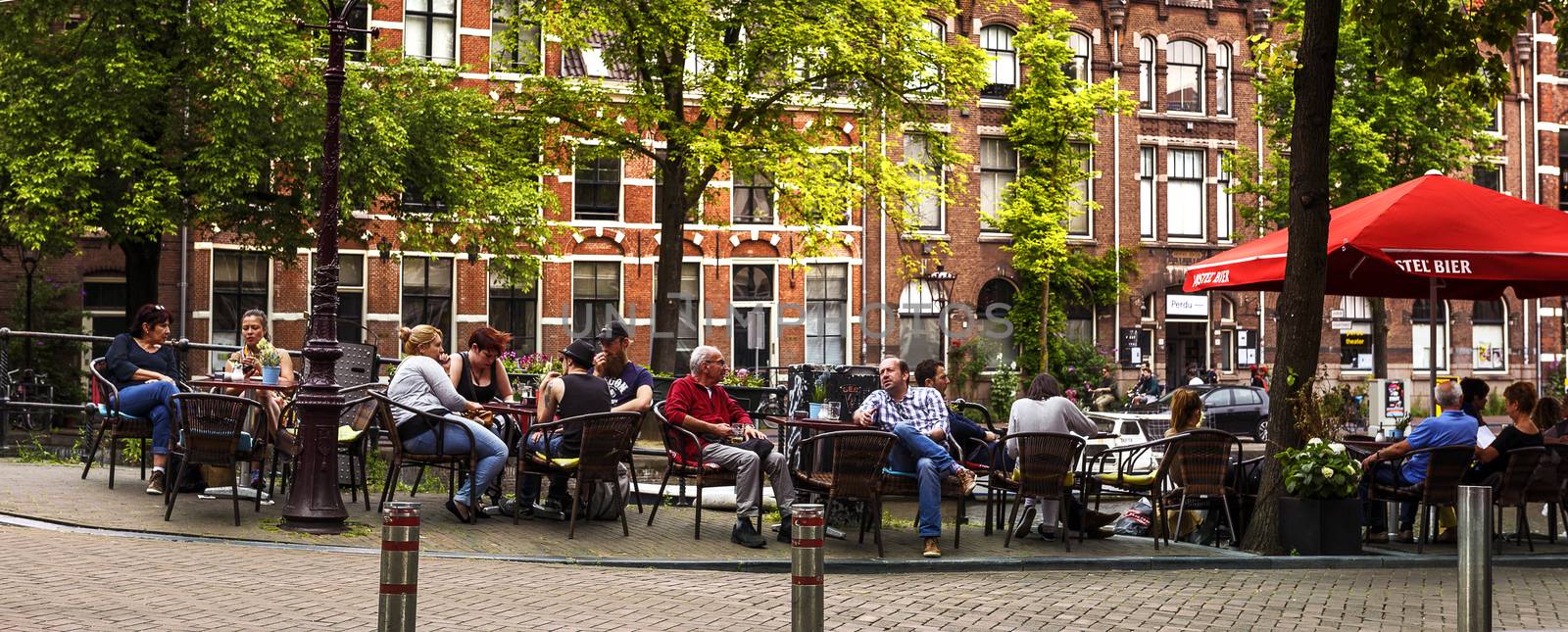 AMSTERDAM, NETHERLANDS, JULY 9  2016. People is relaxing and have a drink on a terrace along the canal in Amsterdam, style of life in Amsterdam, Netherlands.