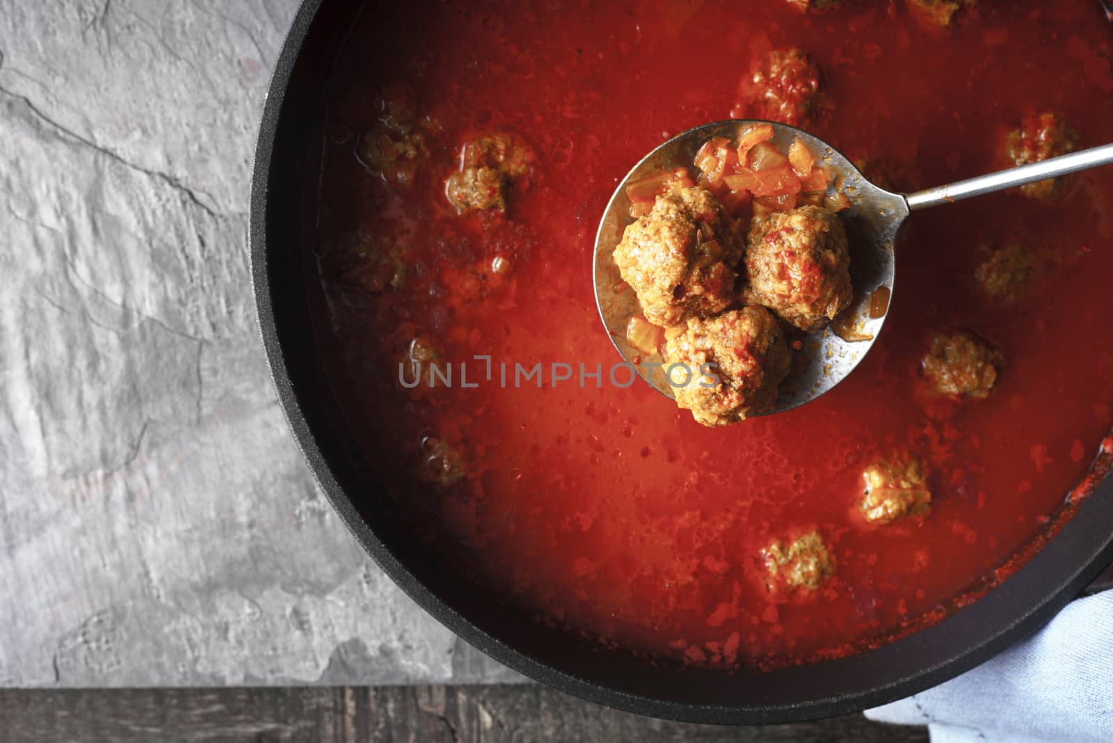 Meatball in the tomato sauce  in the pan on the stone background top view