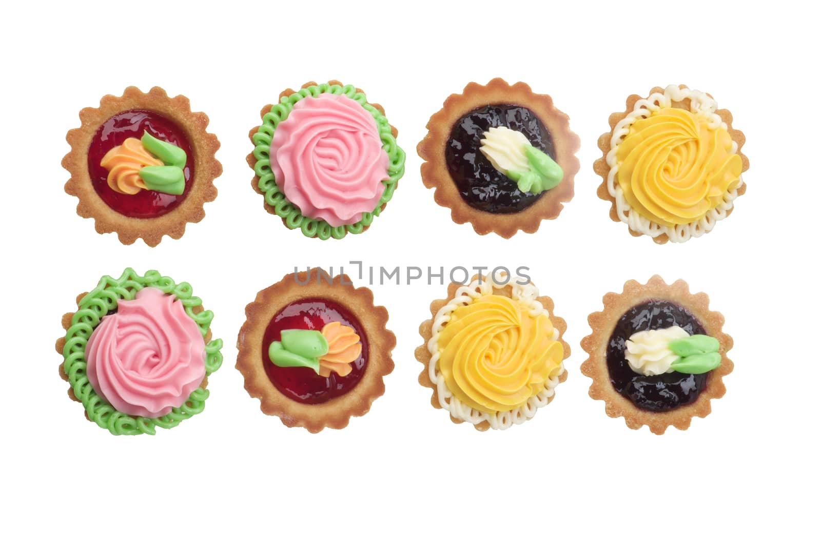 Arrangement of Delicious Little Tarts with Colored Butter Cream, Fruit Jam and Decoration In a Rows isolated on White background. Top View