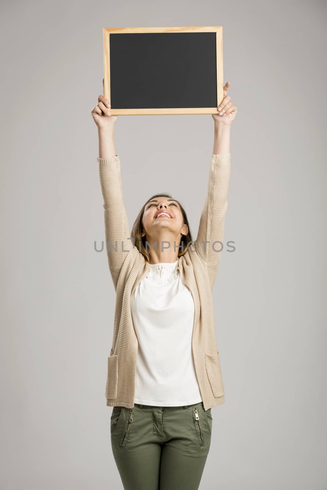 Beautiful and happy woman holding and showing a chalkboard very high