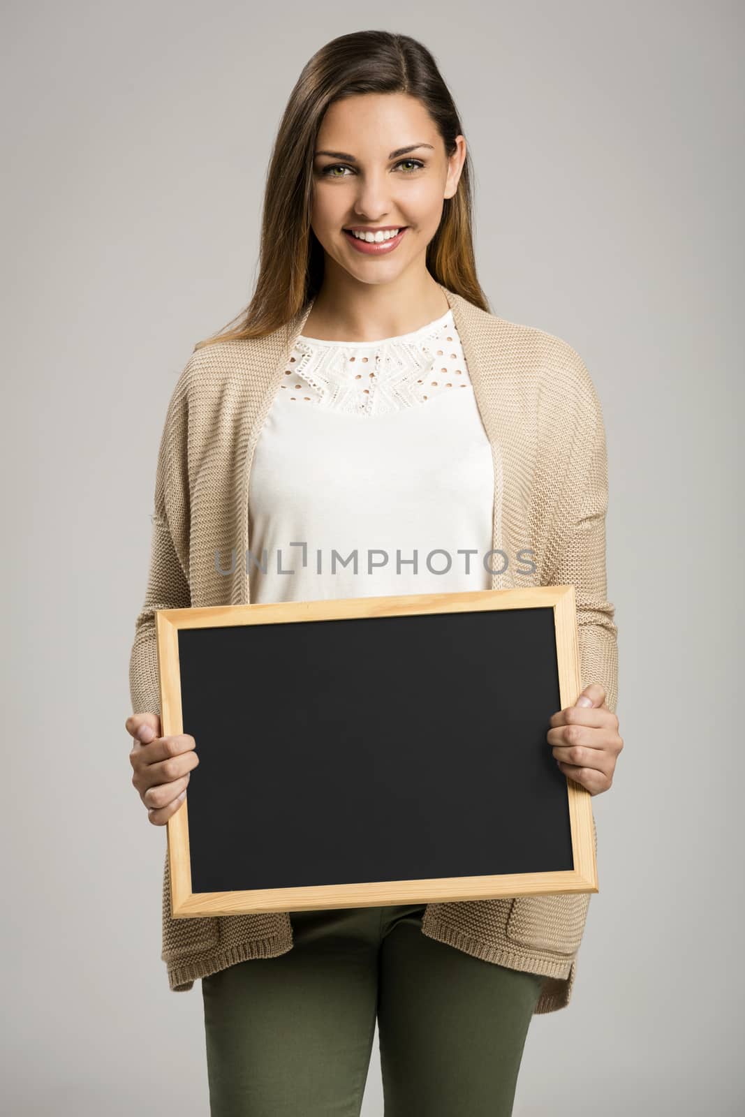 Beautiful and happy woman holding a chalkboard, with copy-space