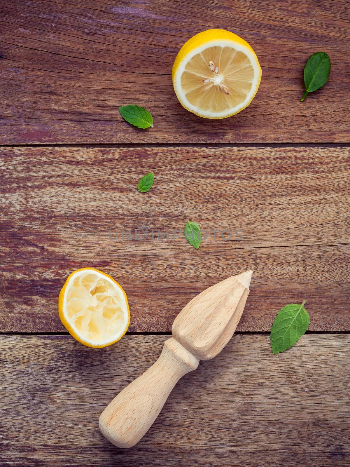 Fresh lemon and wooden juicer for summer juice and cocktail. Fresh lemon sliced and peppermint leaves set up on shabby wooden background flat lay.