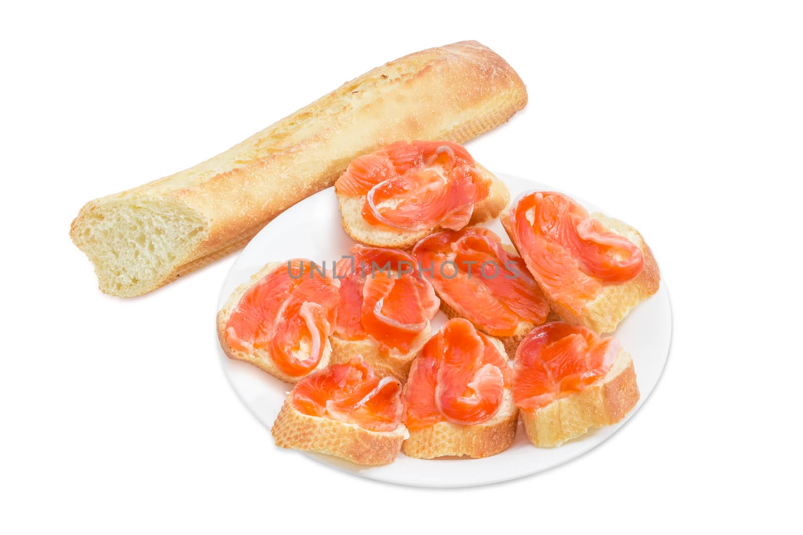 Sandwiches made with pieces of baguette, butter and slices of a salted rainbow trout on white dish and a piece of baguette on a light background
