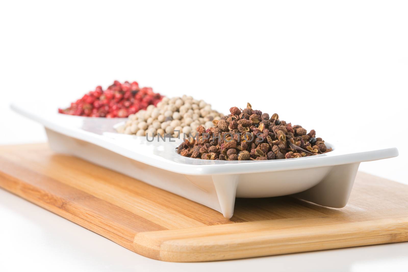 Whole szechuan peppercorns with white and pink peppercorns in the background.