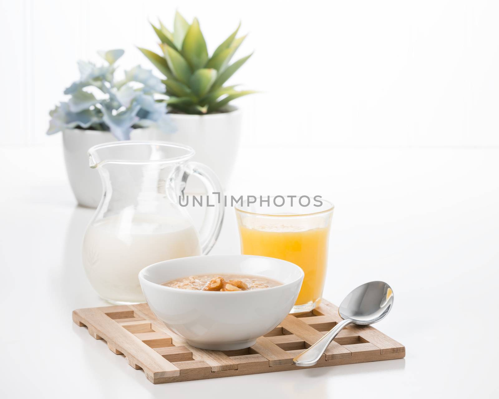 Bowl of maple walnut flavored oatmeal with a pitcher of cream.