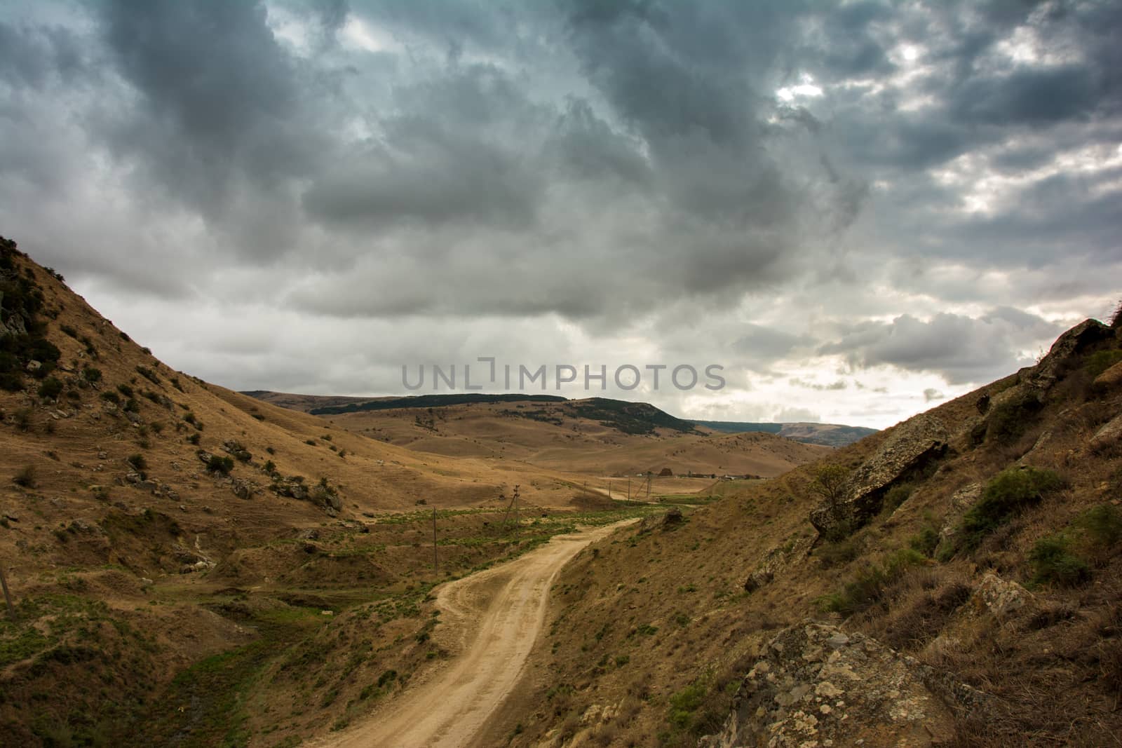 Storm clouds and the road stretches into the distance in the Caucasus mountains