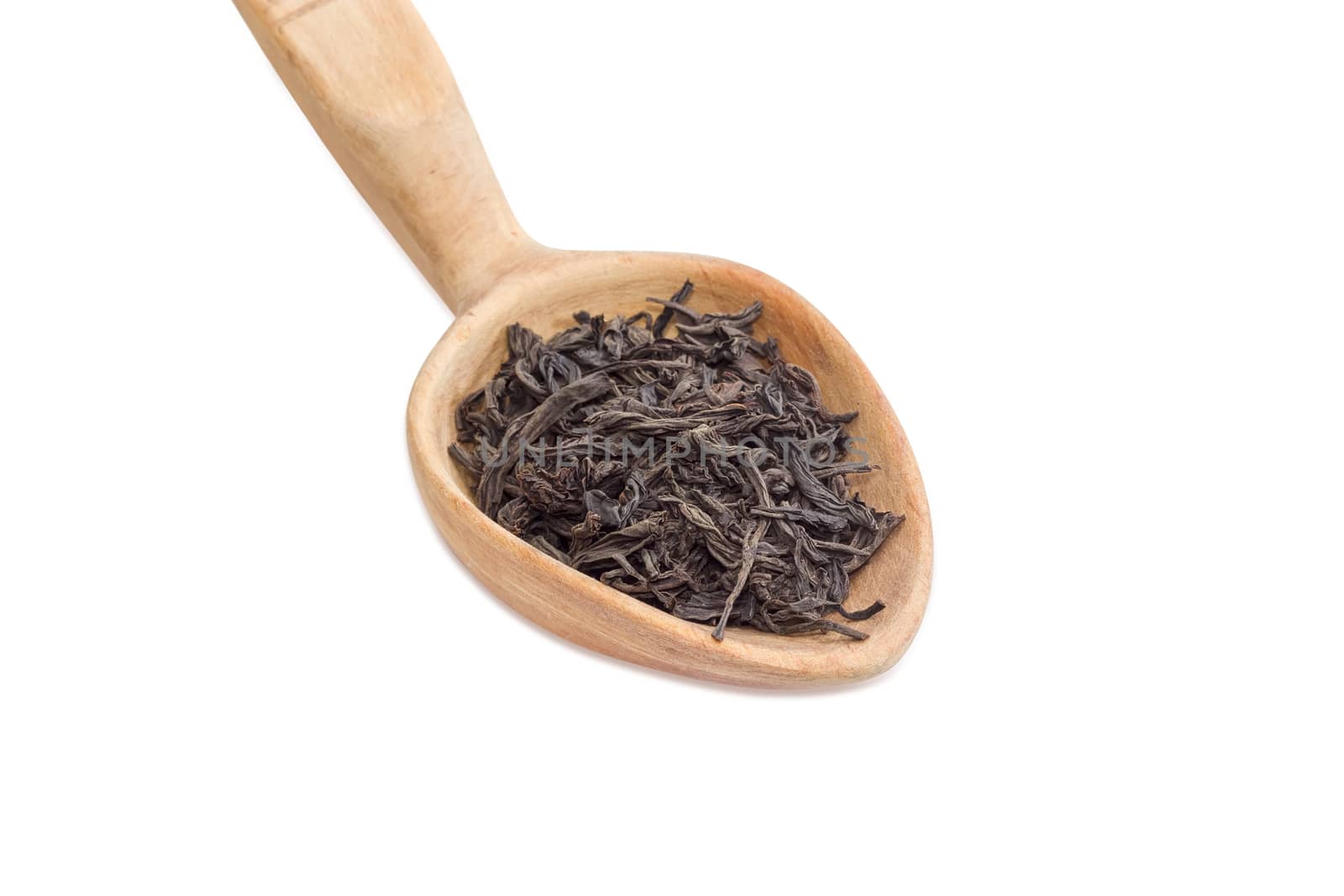 Dried leaf of black tea in a wooden spoon on a light background closeup
