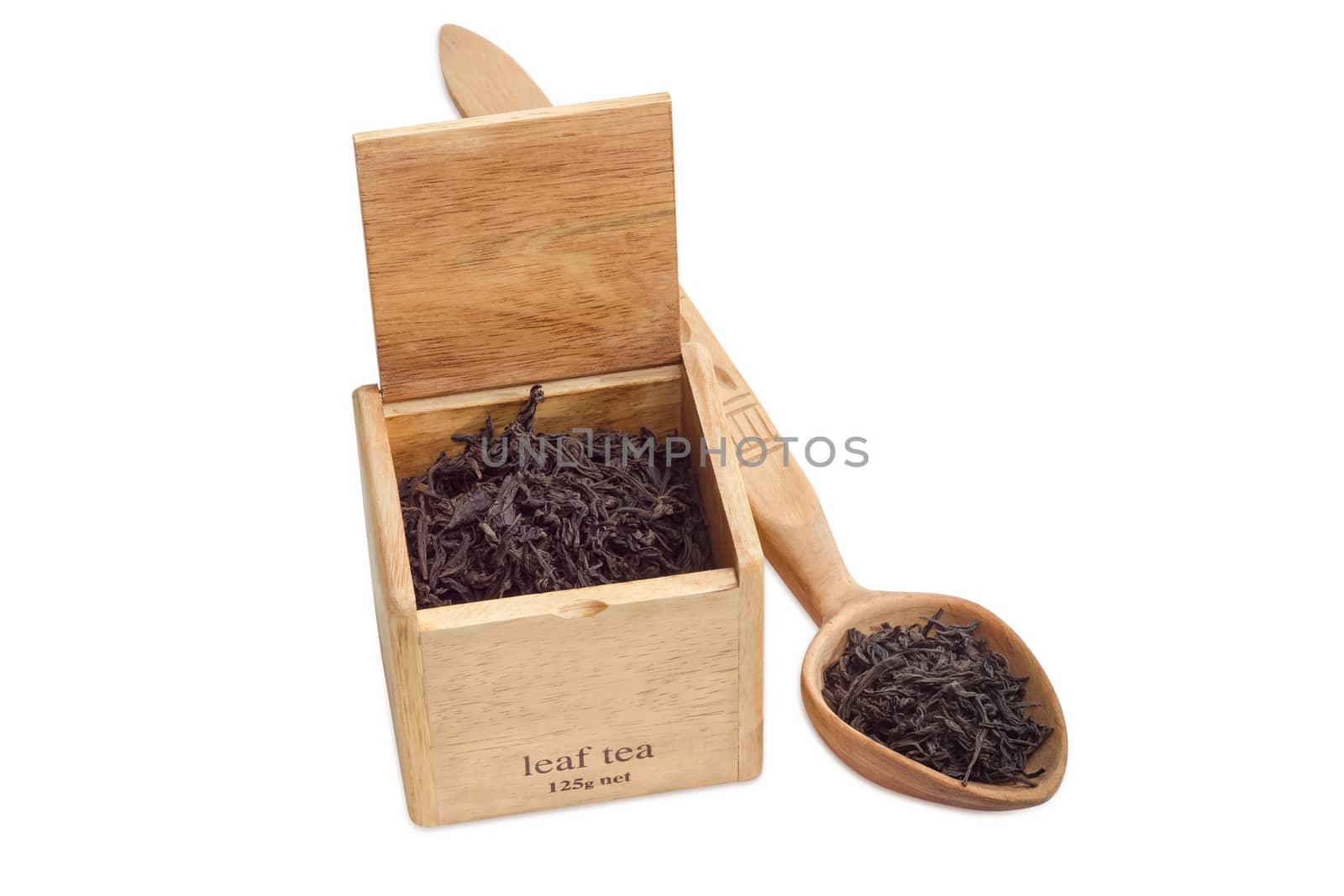 Large leaf of black tea in a wooden box and wooden spoon on a light background closeup
