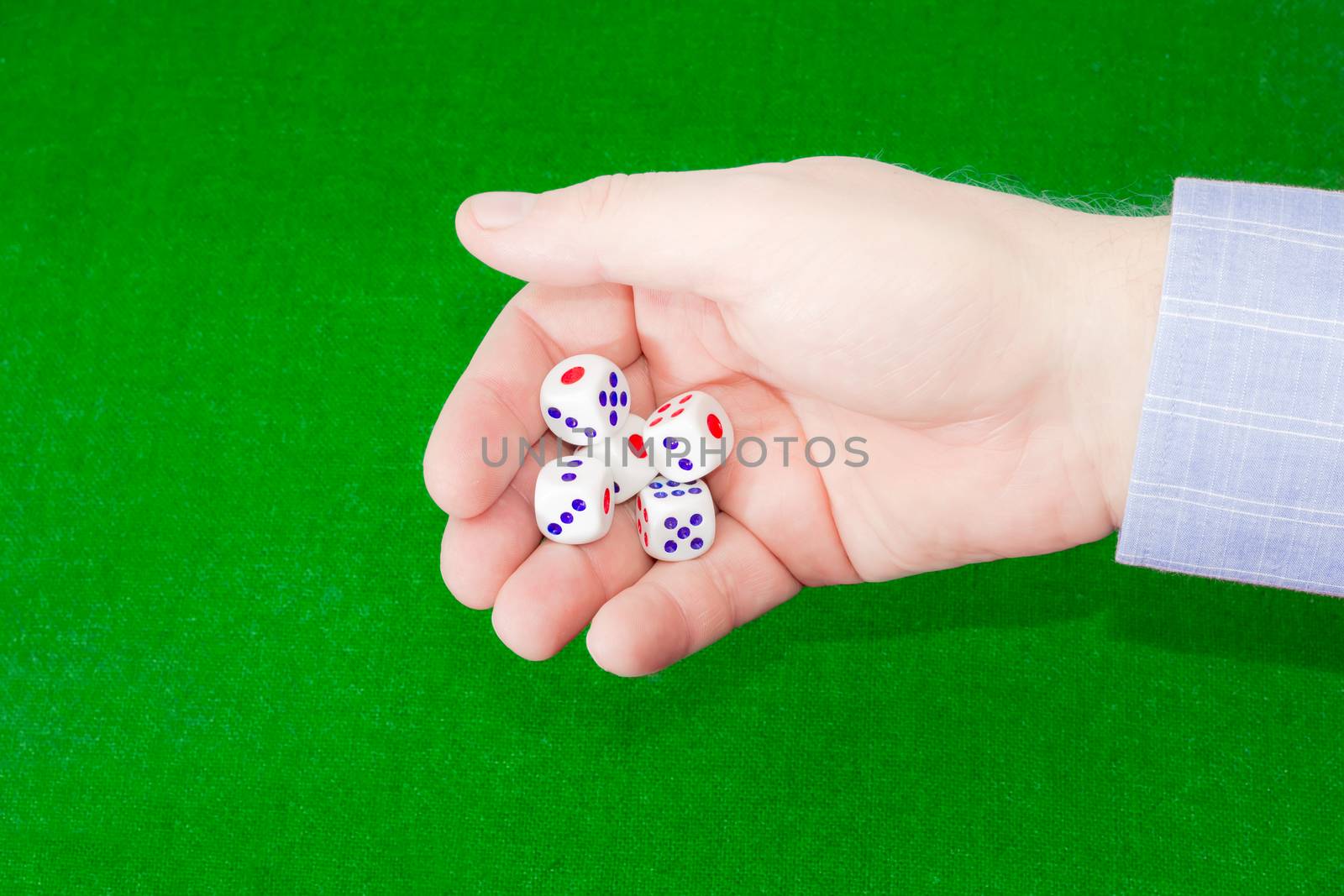 Traditional dice in male hand over table with green cloth by anmbph