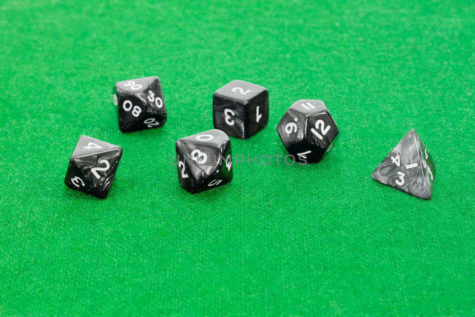 Set of specialized polyhedral dice with numbers used in role-playing games on a table with green cloth
