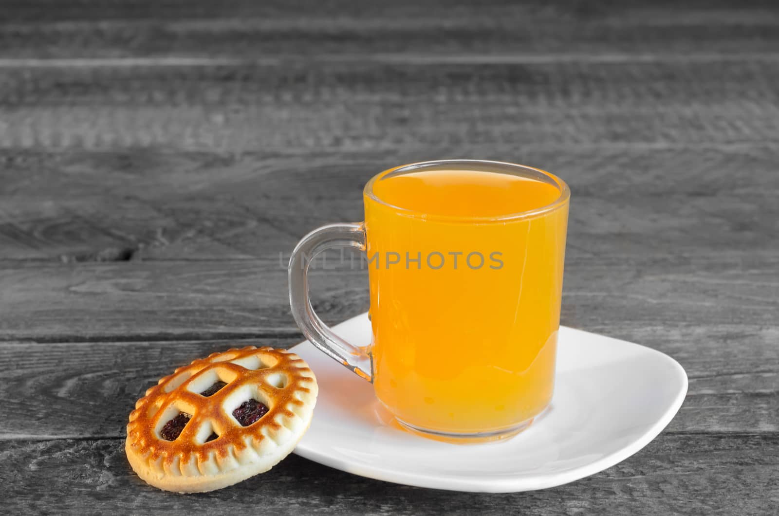 Cookies and orange juice in a circle on a grey wooden background. Selective focus.