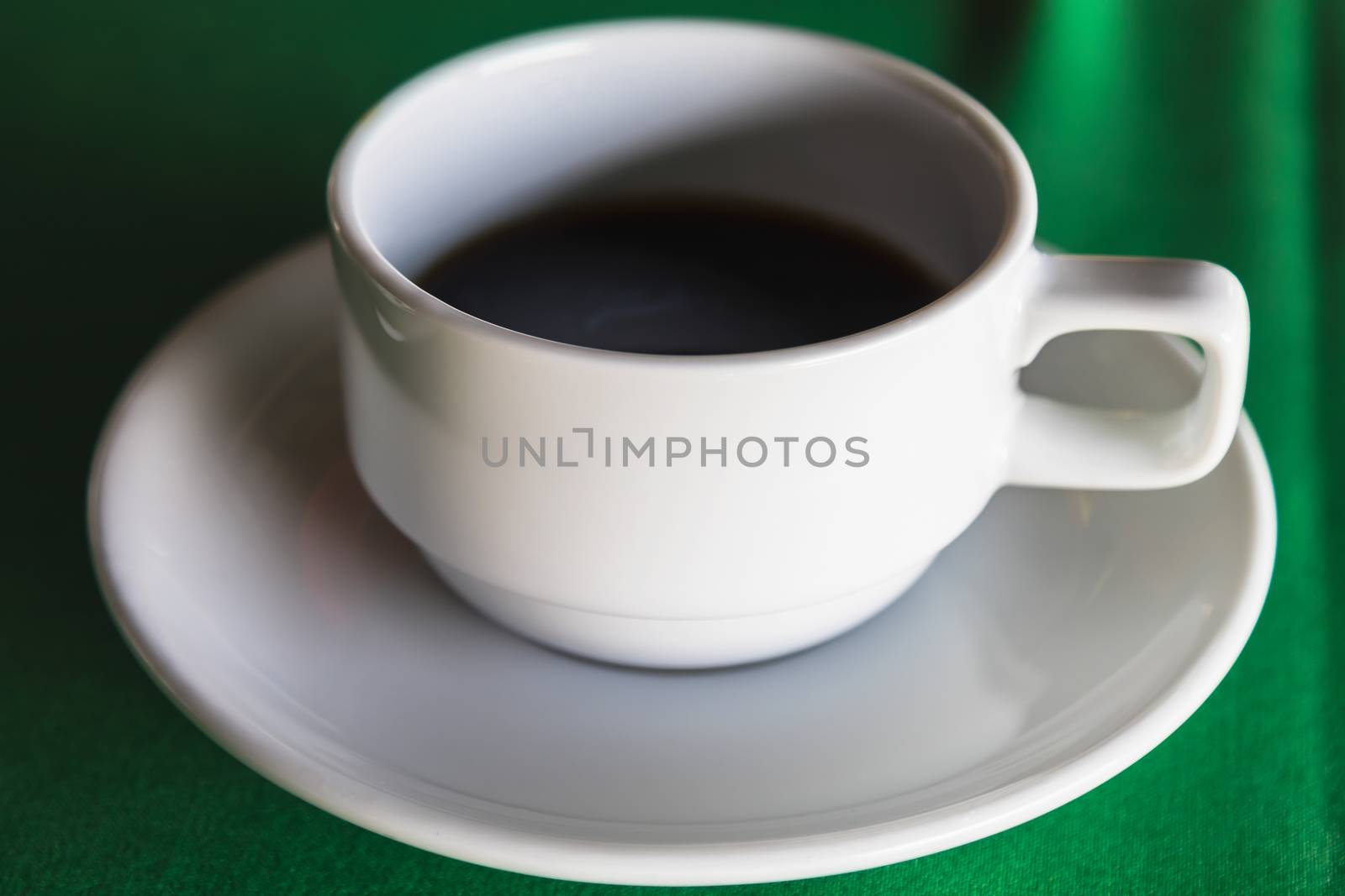 A cup of hot coffee on green background