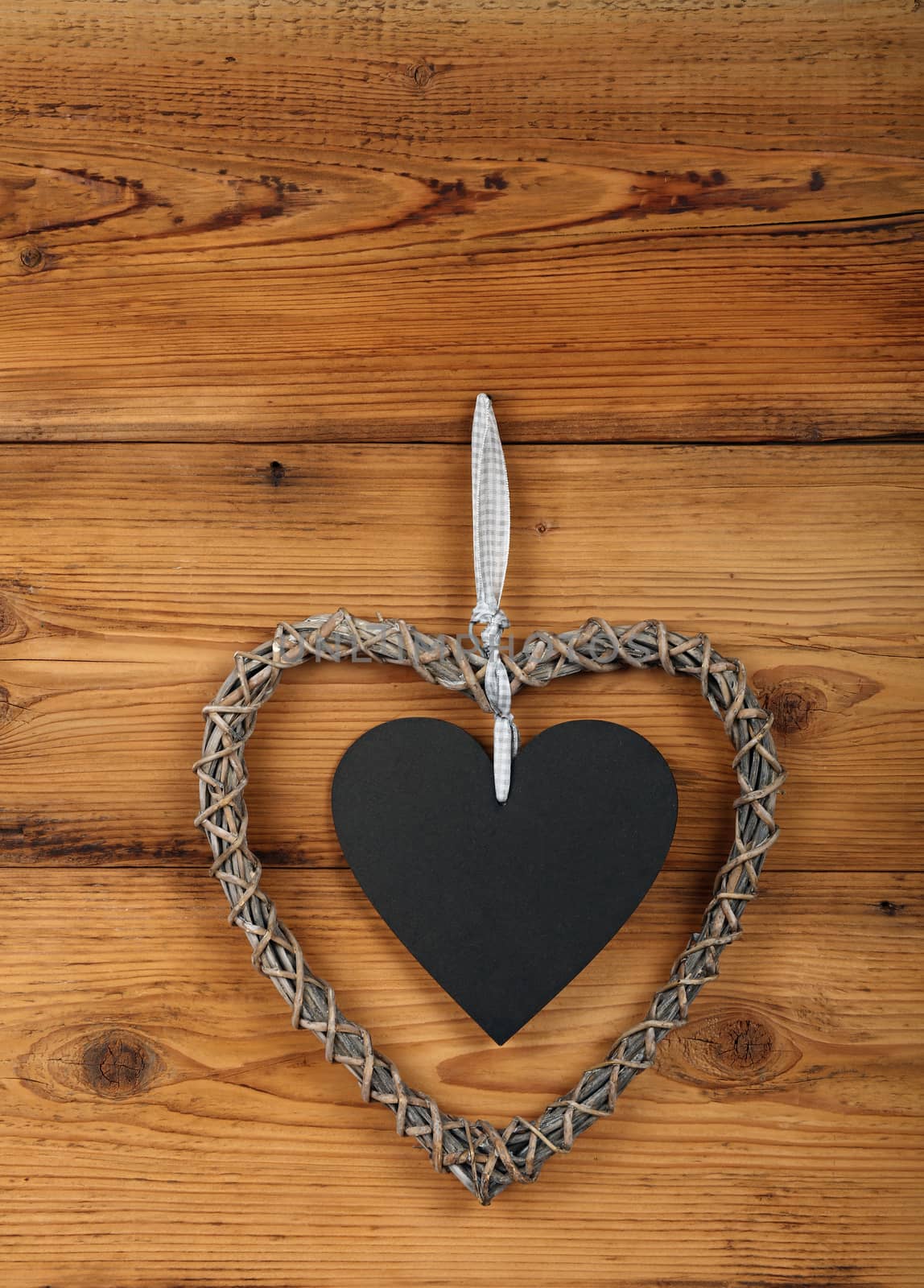 Heart shaped handmade wicker braided frame with chalk blackboard copy space on old vintage rustic brown wooden wall, close up
