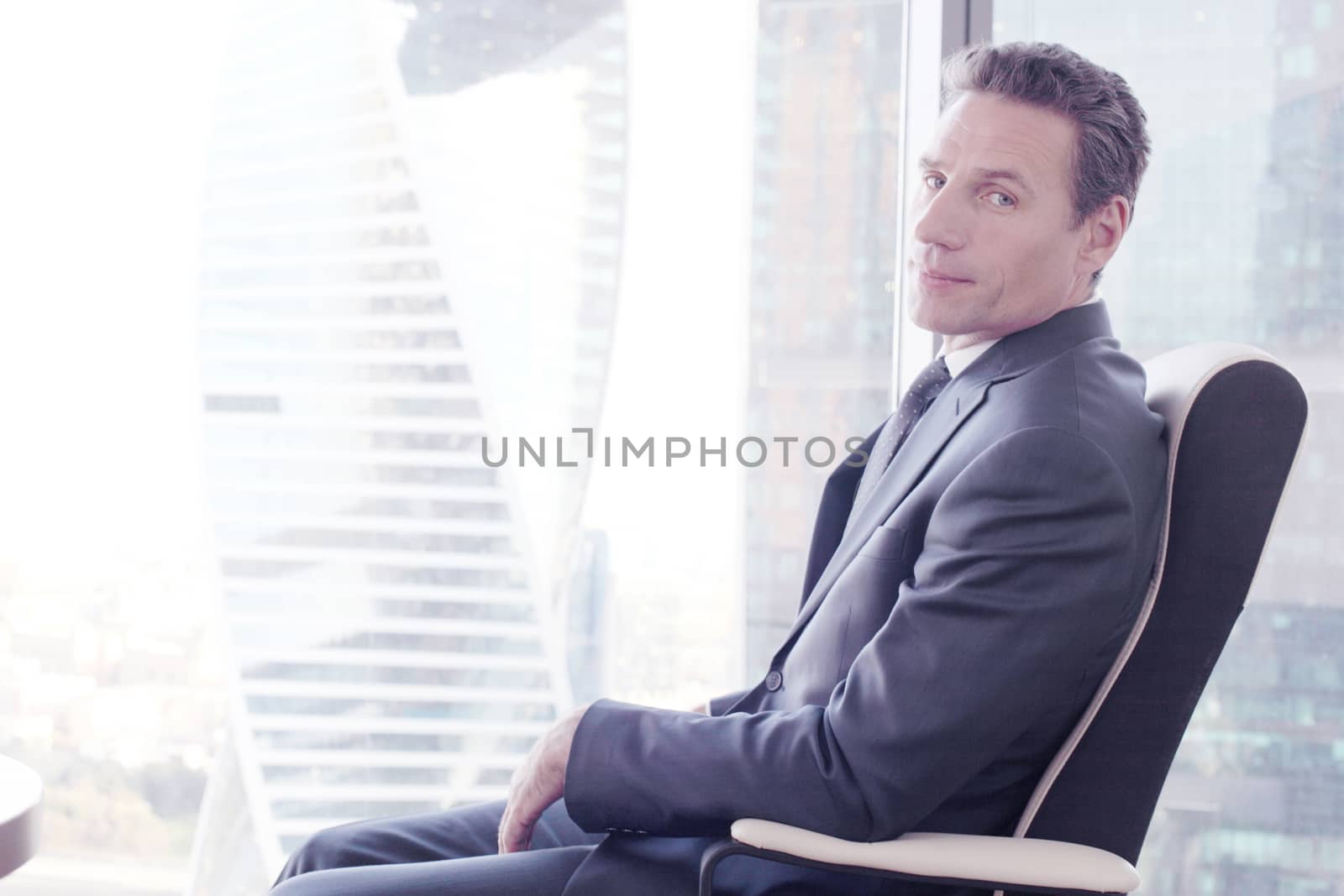 Portrait of a business man sitting on armchair against the window