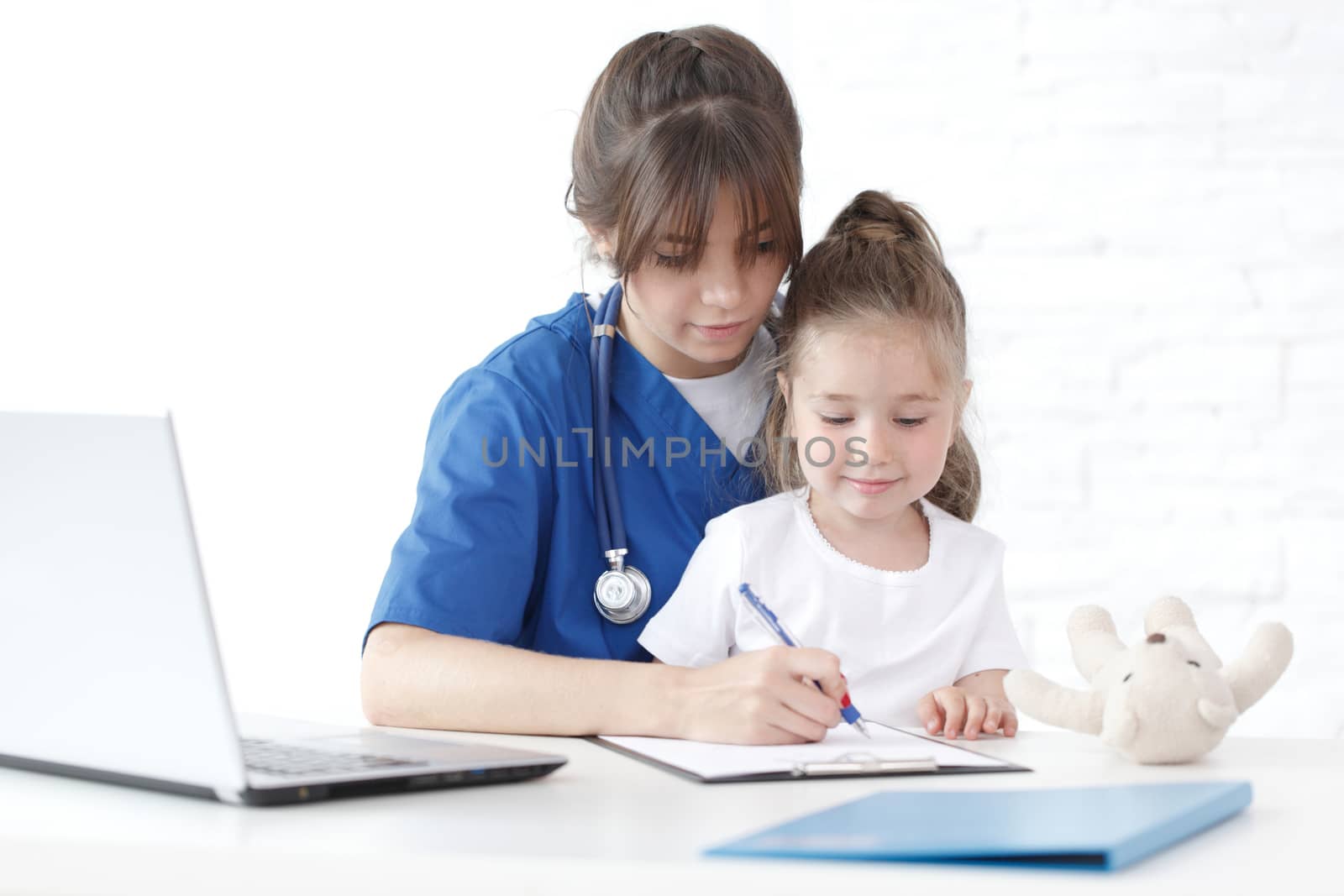 Child patient and young female doctor writing diagnosis