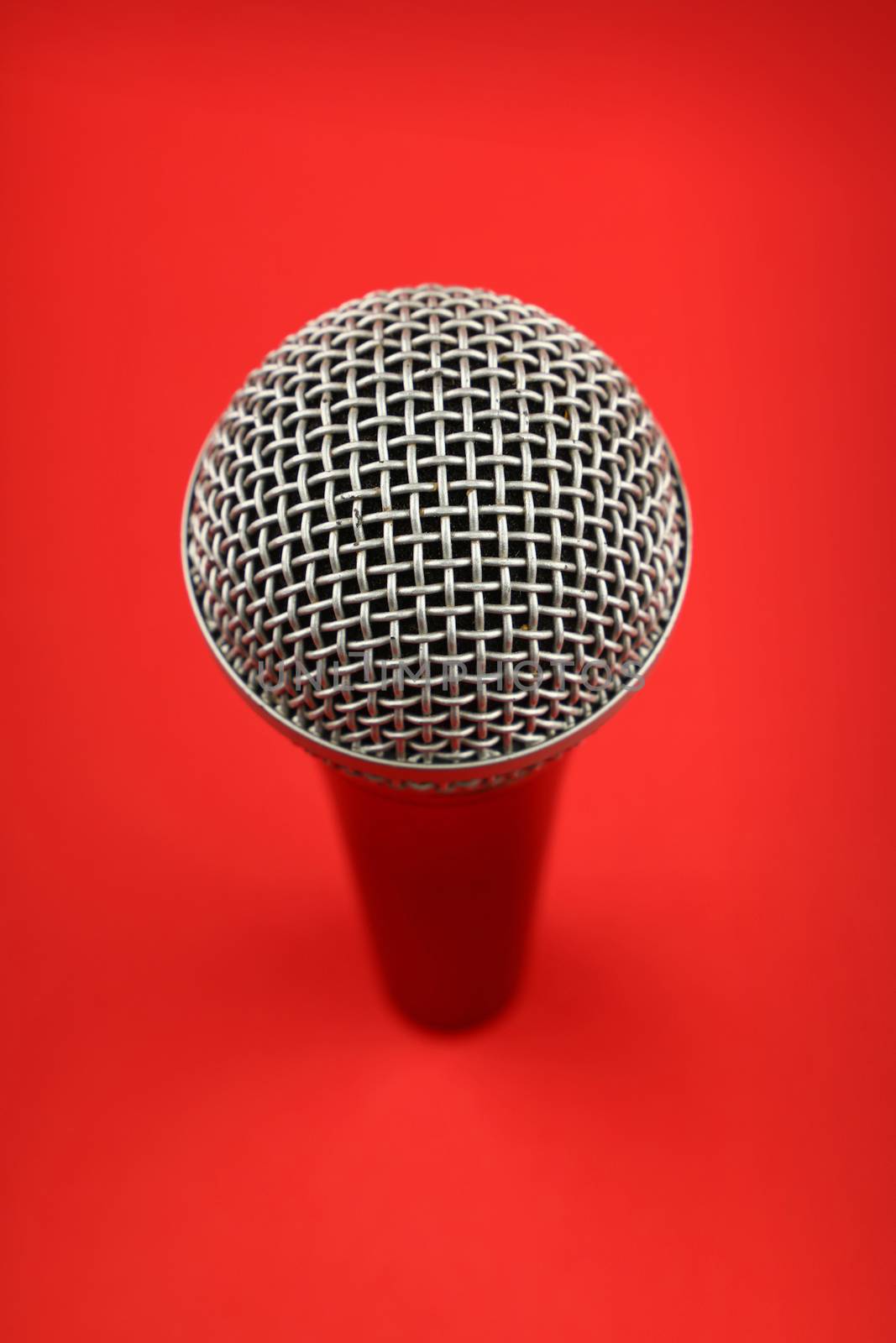 Vocal microphone high angle view close up over red background, personal perspective