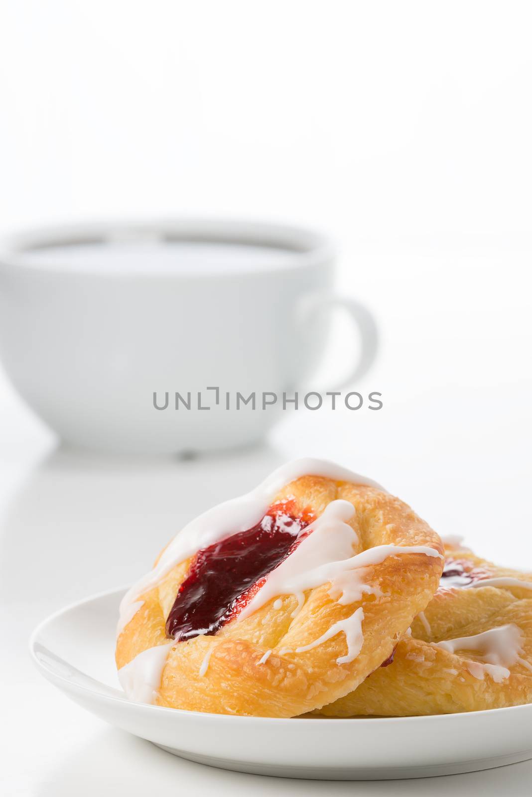 Fresh raspberry danish with coffee in the background.