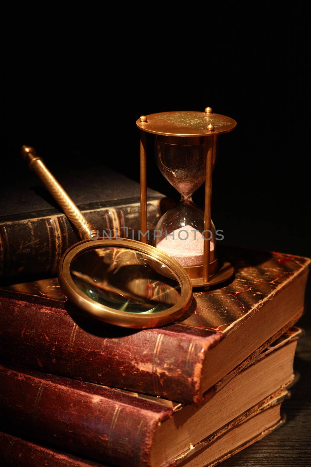 Vintage still life. Magnifying glass and hourglass near old books